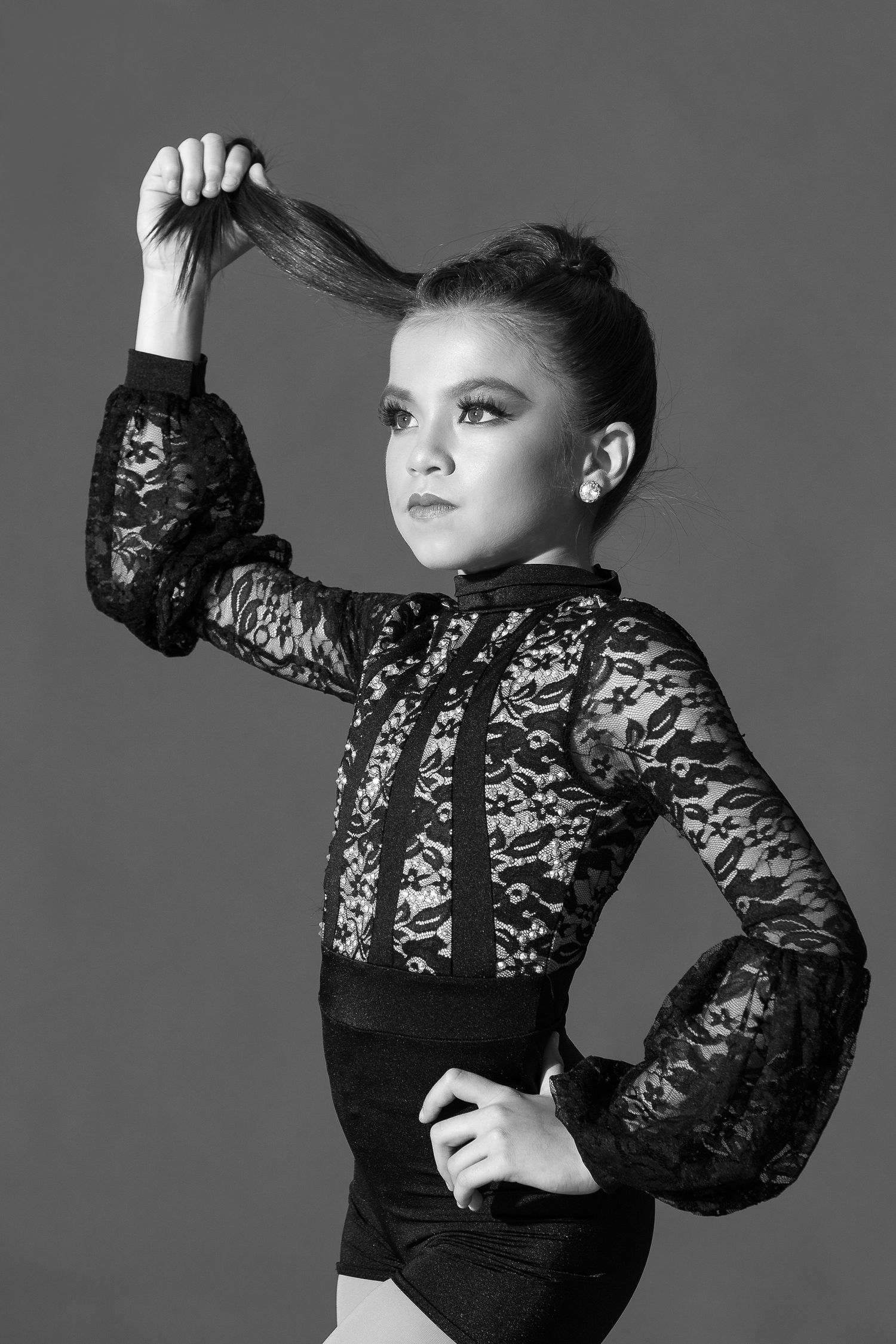 Black and white fashion photo with lace sleeves and dramatic lighting showing a striking dance or modeling pose.
