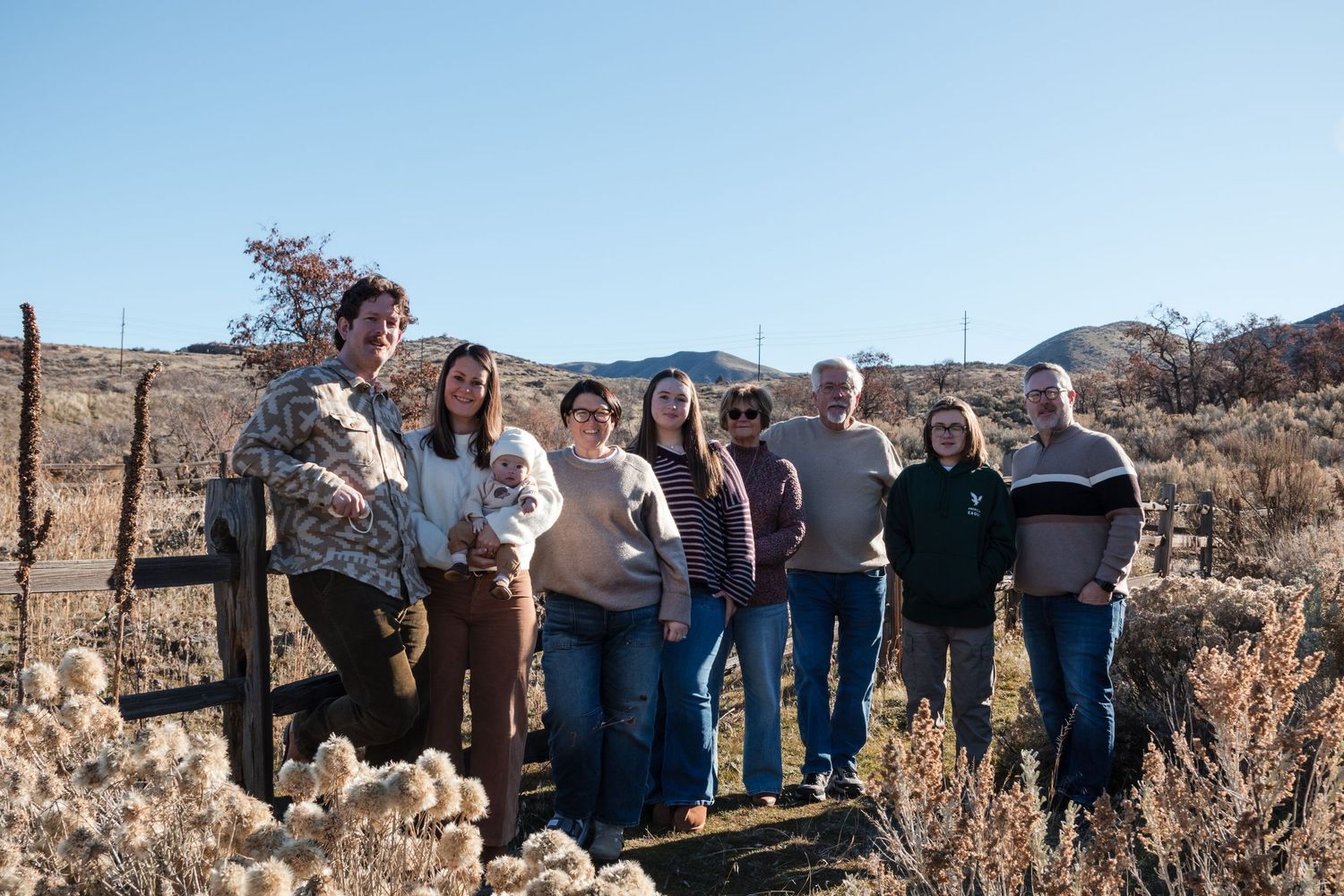 Family group photo outdoors in a desert landscape with mountains and clear blue sky in the background.