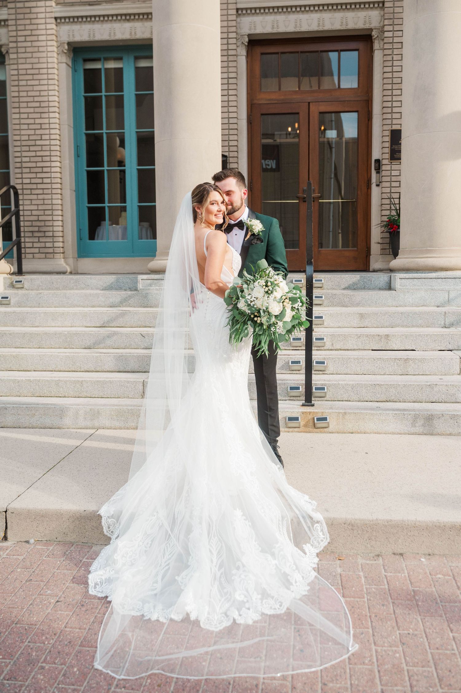 Romantic wedding portrait in front of historic brick building with columns.