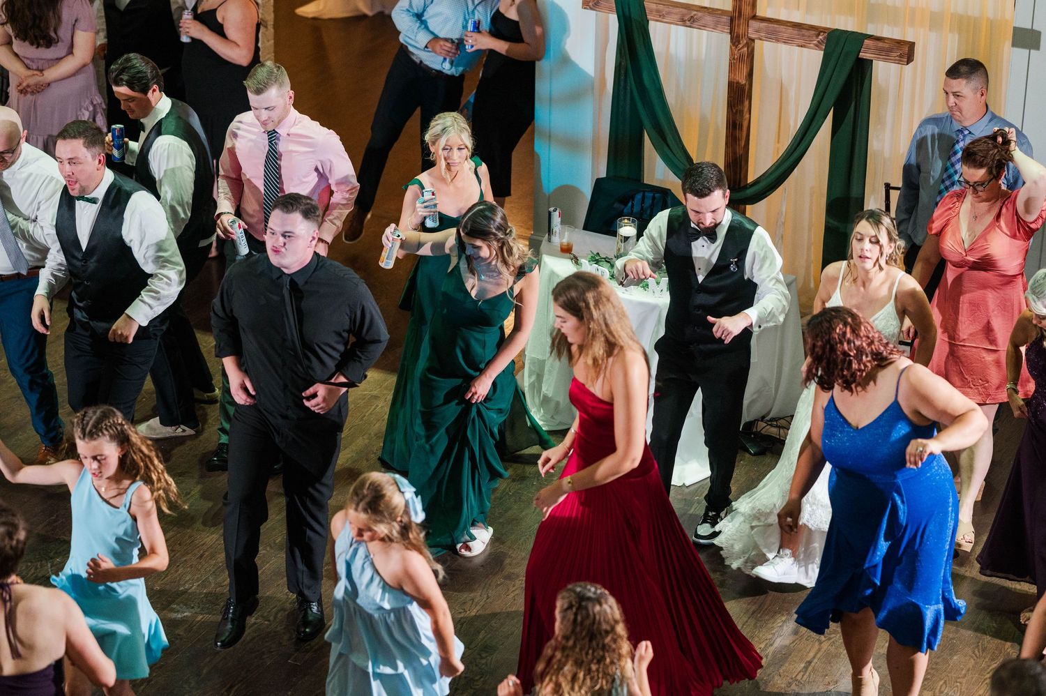 Guests dancing in formal attire at a wedding reception with colorful dresses.