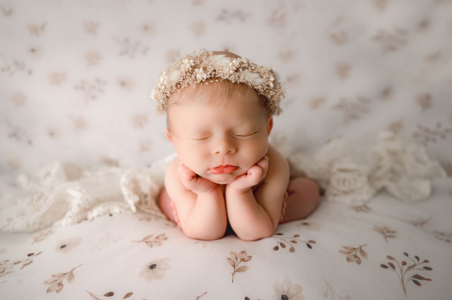 Close-up of tiny newborn baby toes against soft white floral fabric.