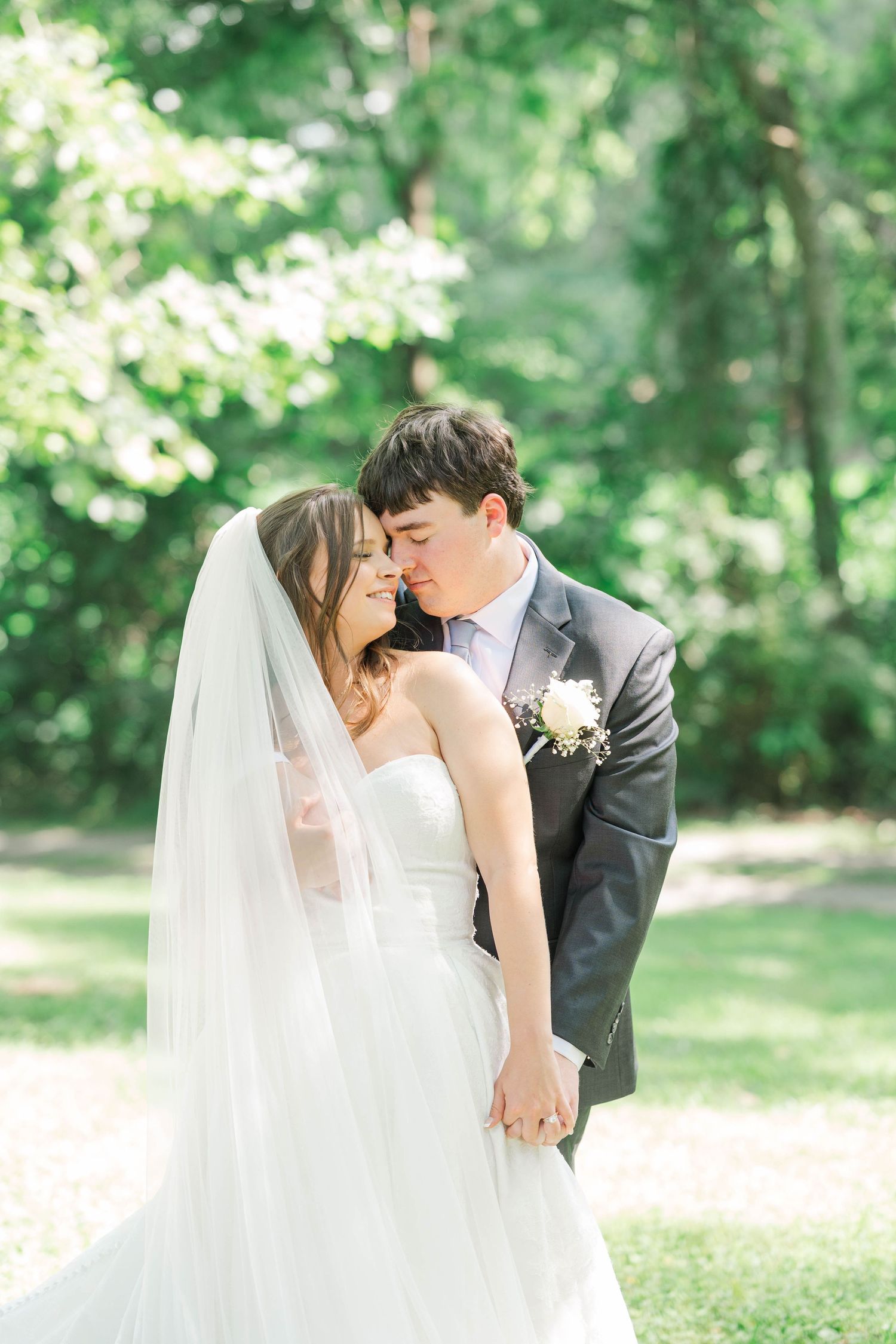 Intimate wedding moment captured in sunlit garden setting.