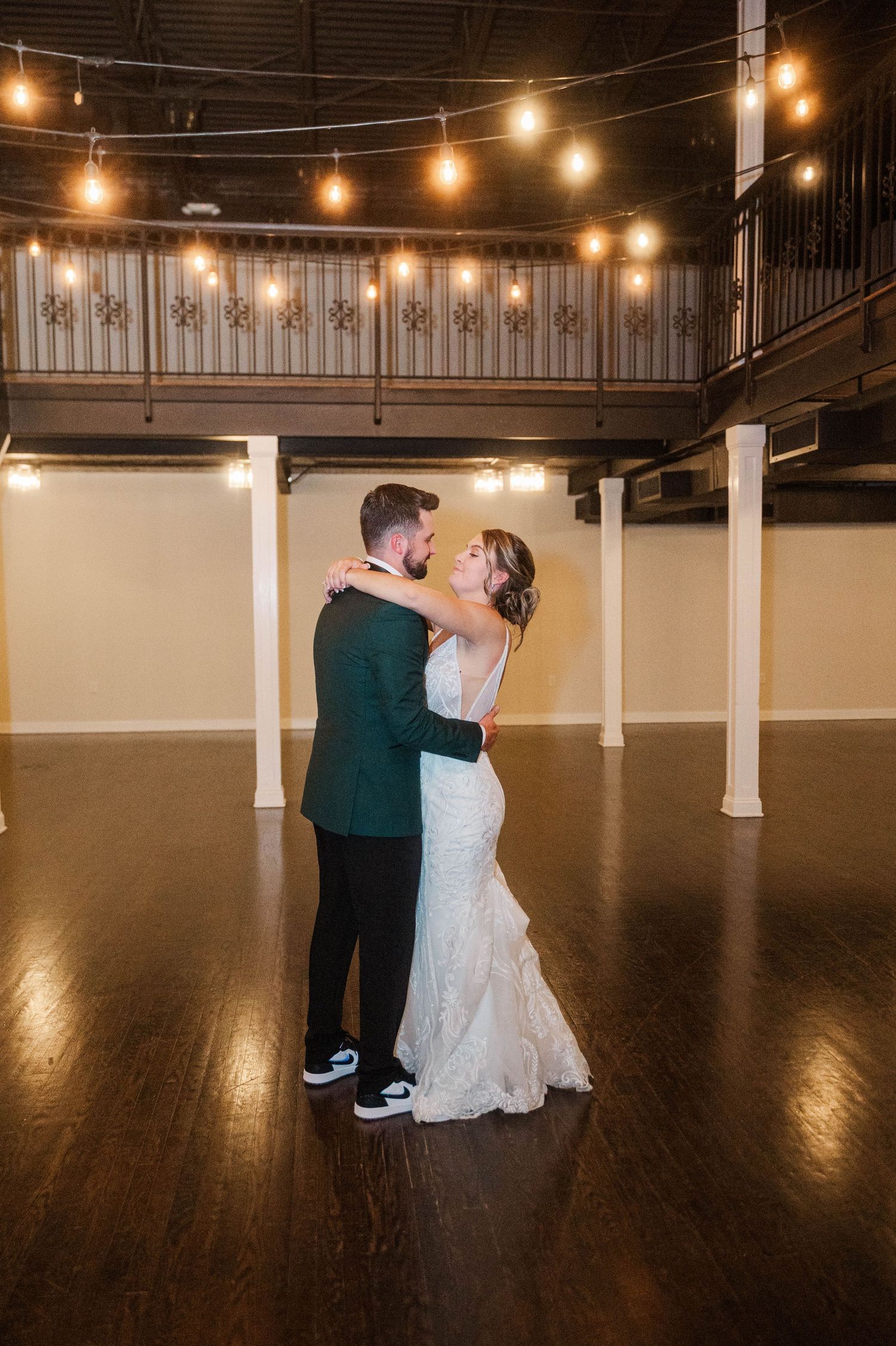Couple sharing intimate dance moments in a spacious ballroom with warm lighting.