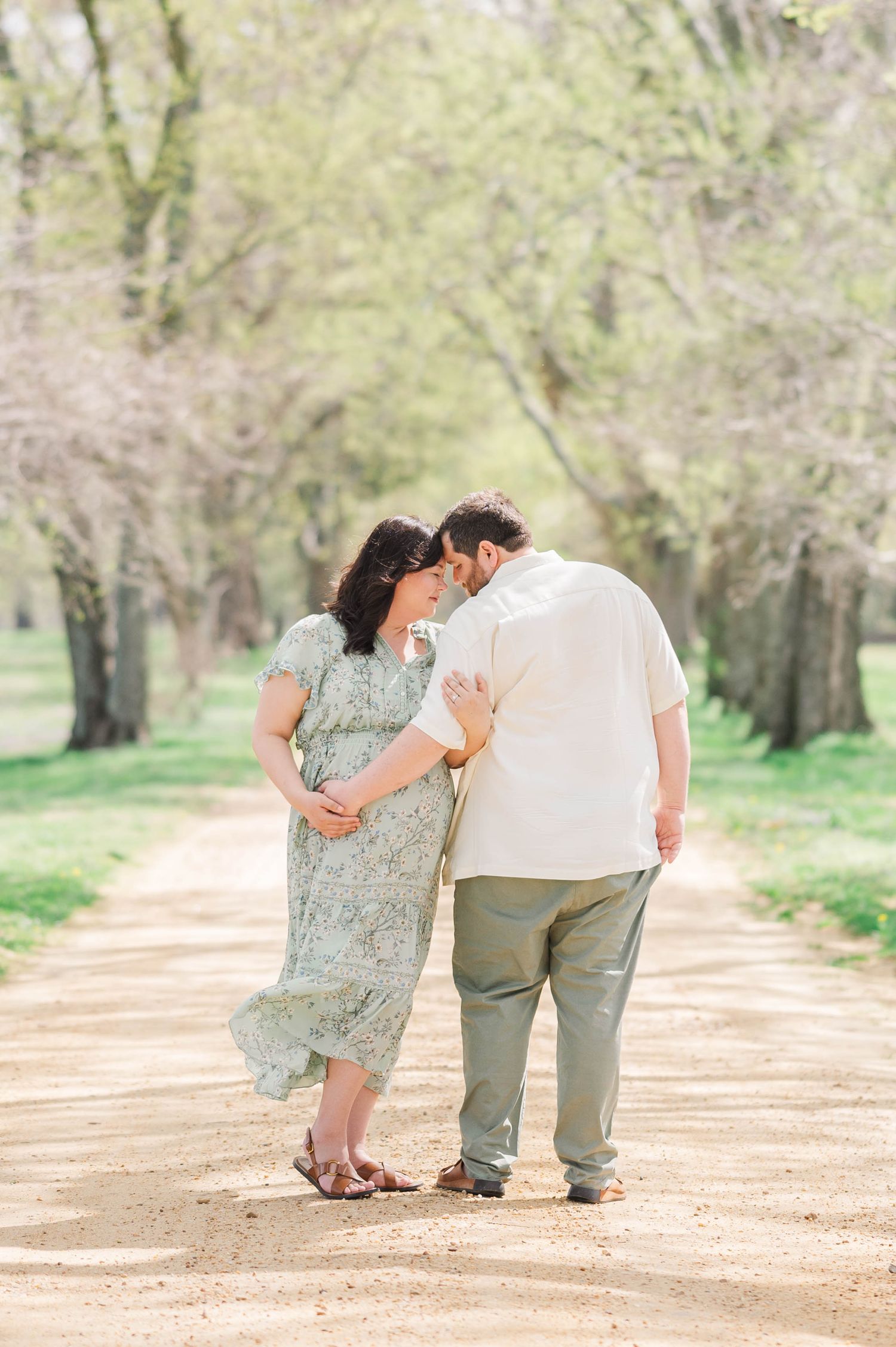 maternity session on a tree-lined dirt path during a romantic photoshoot.