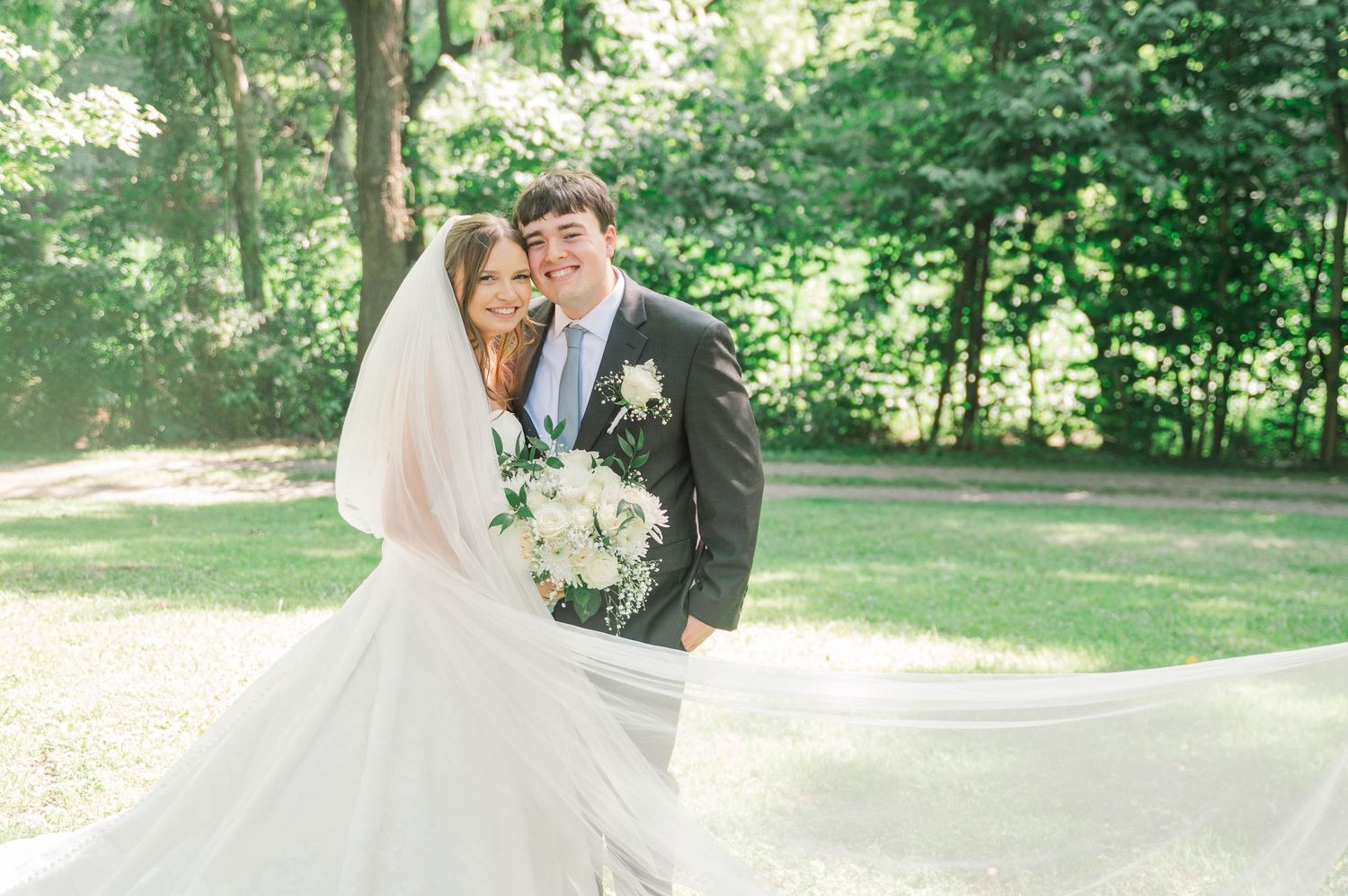 Romantic wedding photography session in a sunlit wooded area.