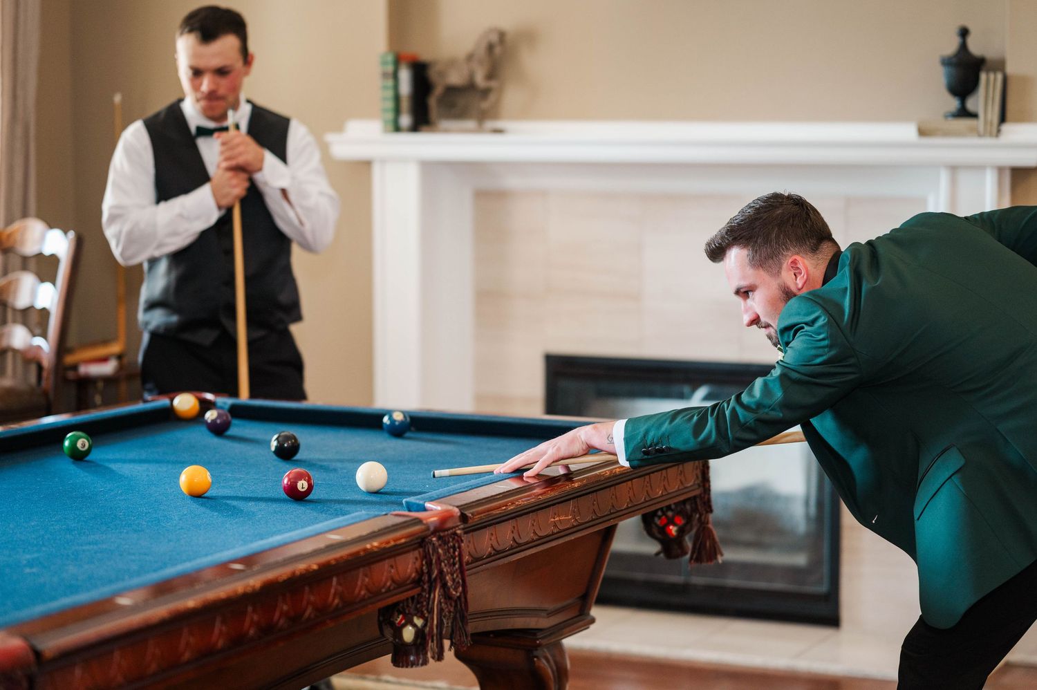 Men in formal attire play pool at a wedding venue.