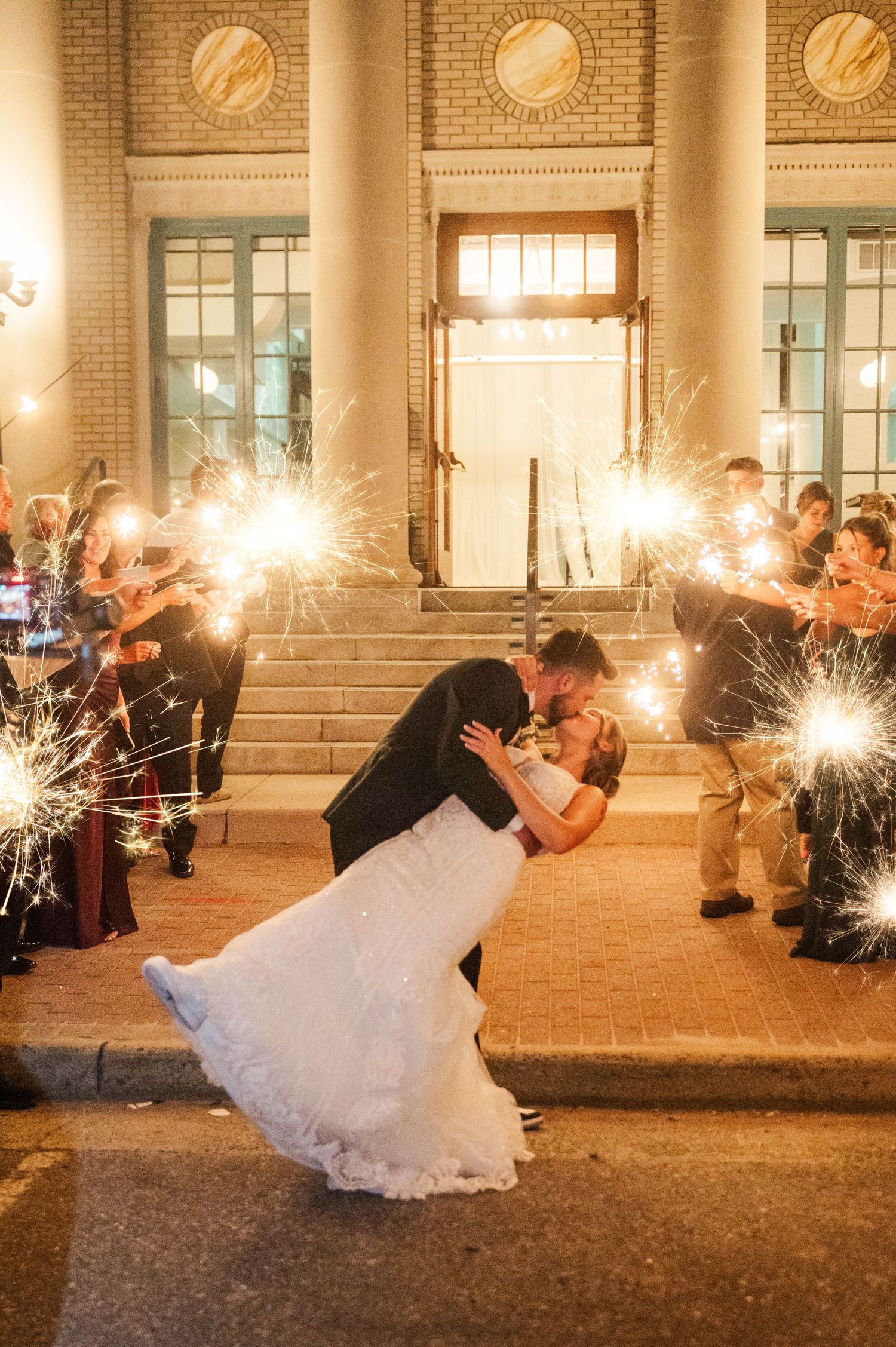 Dramatic sparkler exit sequence outside a brick building at night.