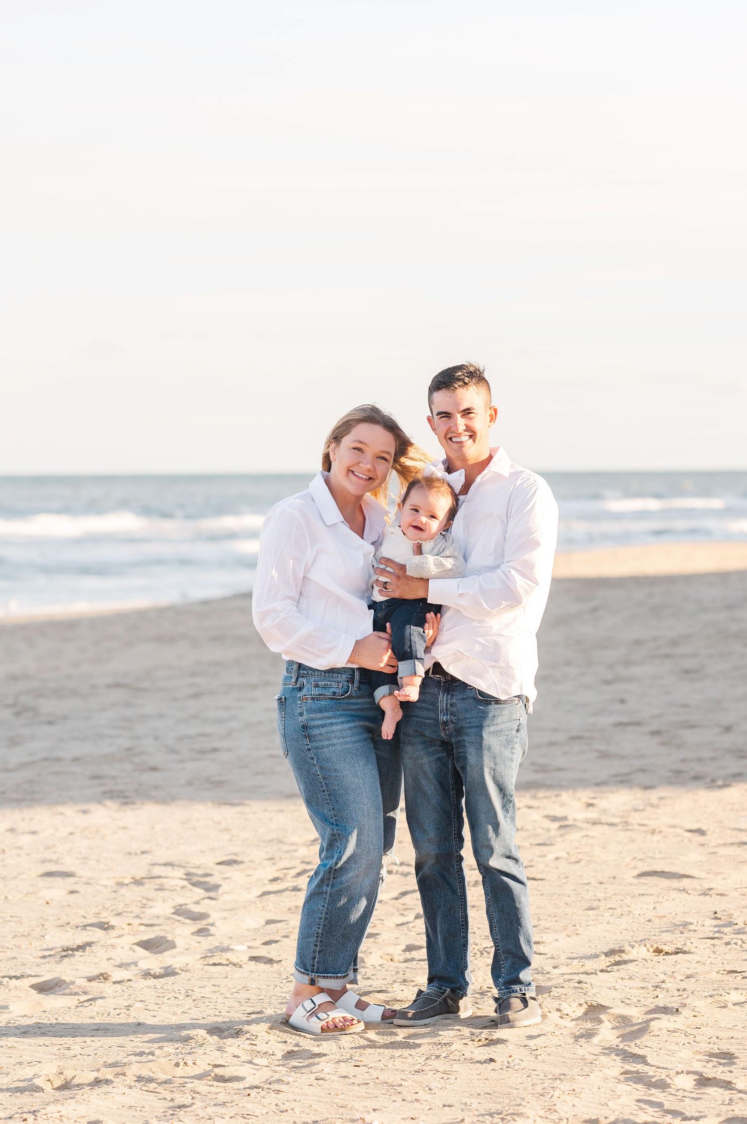 Family playing together on sandy beach during sunset.