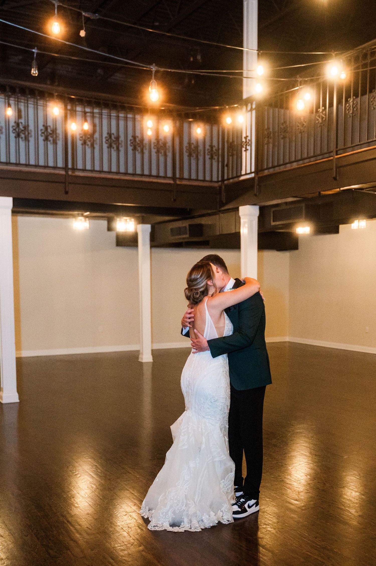 Romantic dance sequence in an elegant venue with string lights and hardwood floors.