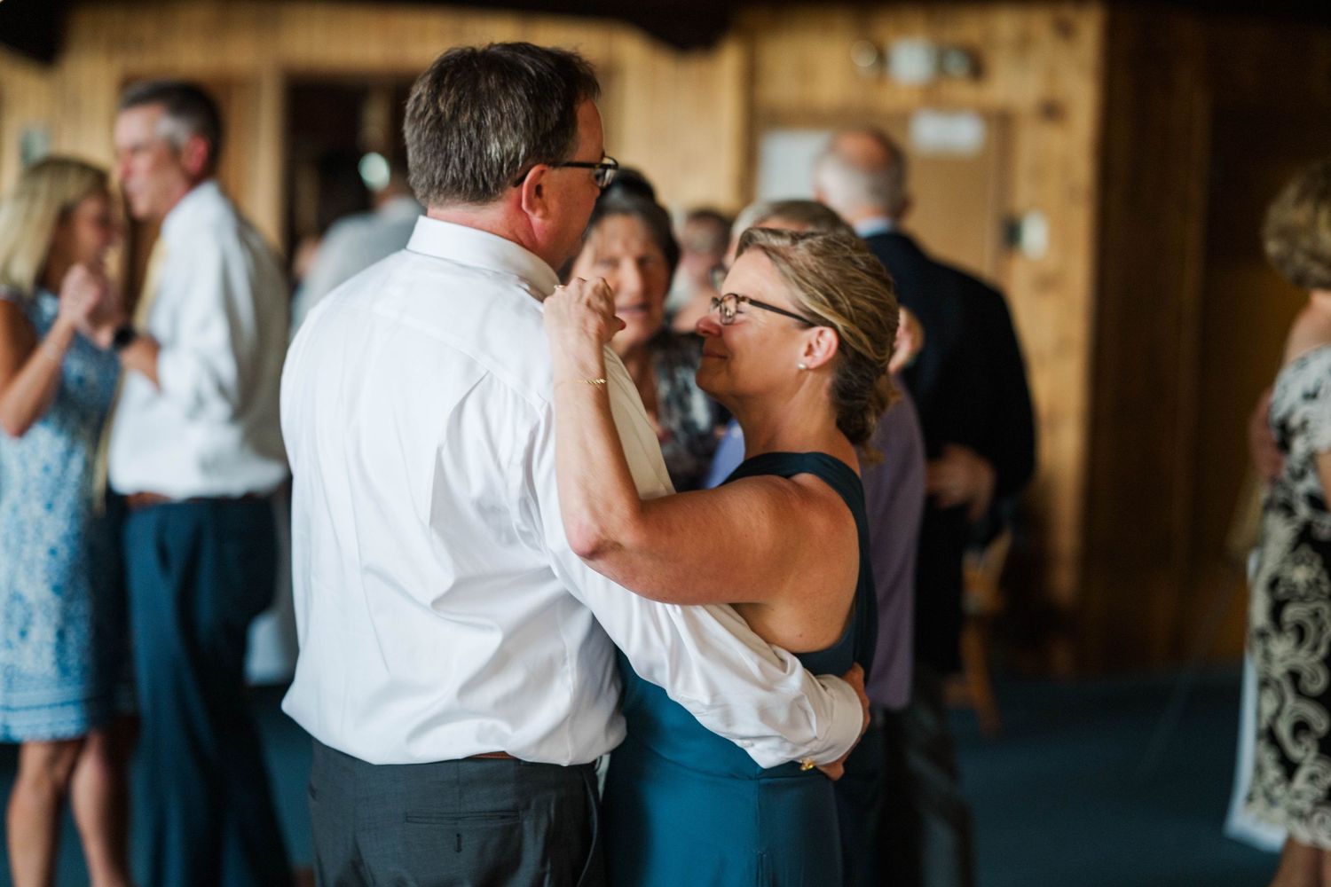 Wedding guests dancing and embracing during a reception celebration.