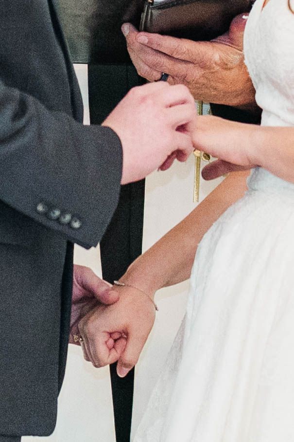 Close-up shots of wedding ring exchange between couple in formal attire.