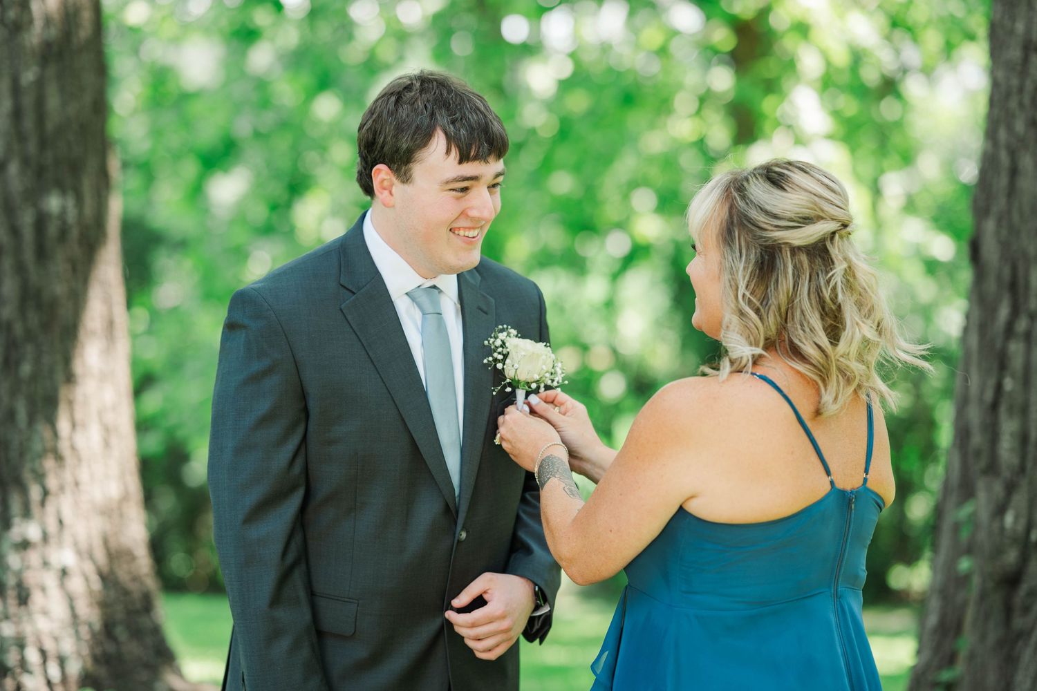 Couple sharing intimate moment during first look in wooded outdoor setting.