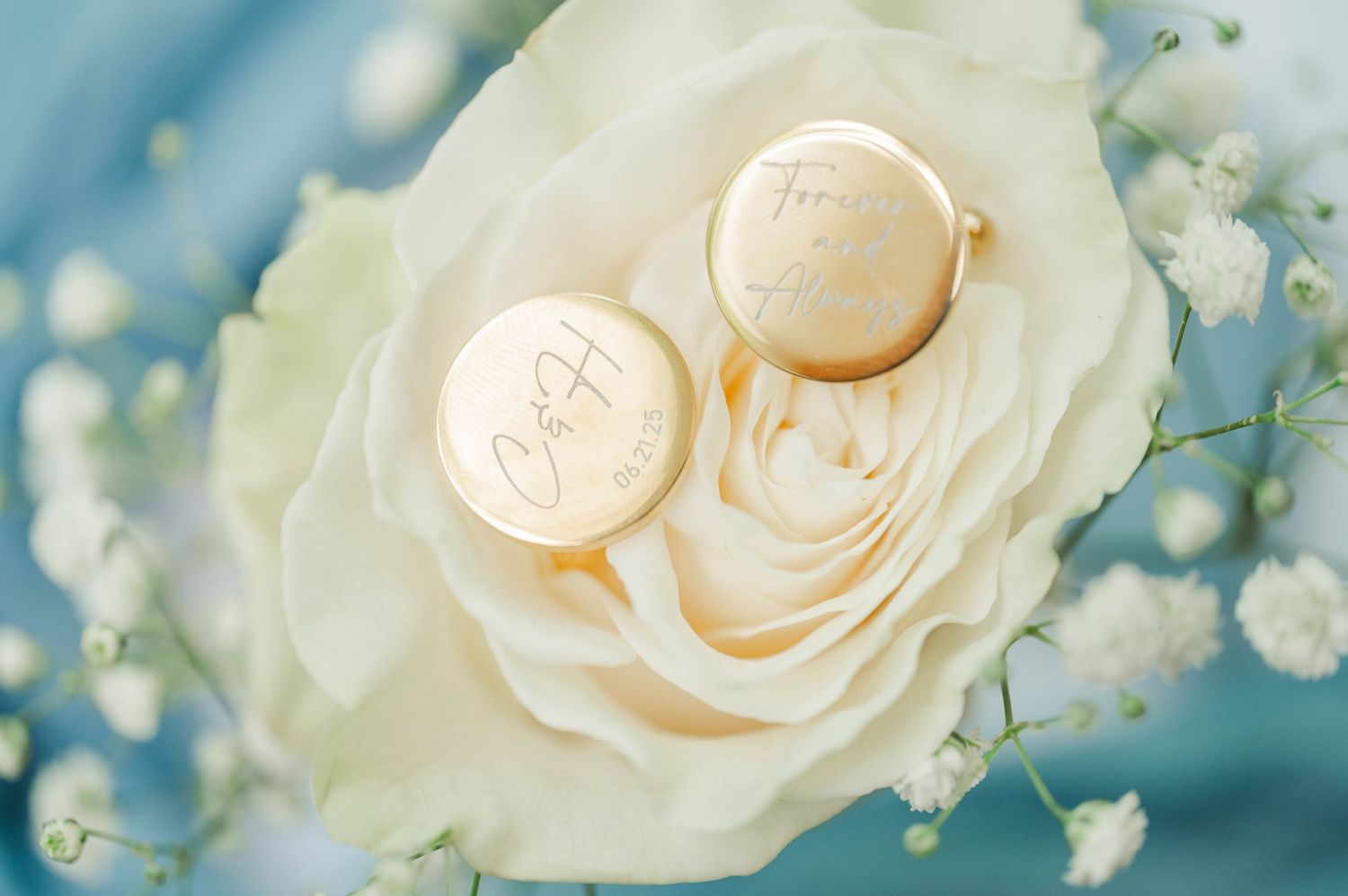 Delicate cream roses and baby's breath flowers arranged with soft teal background.