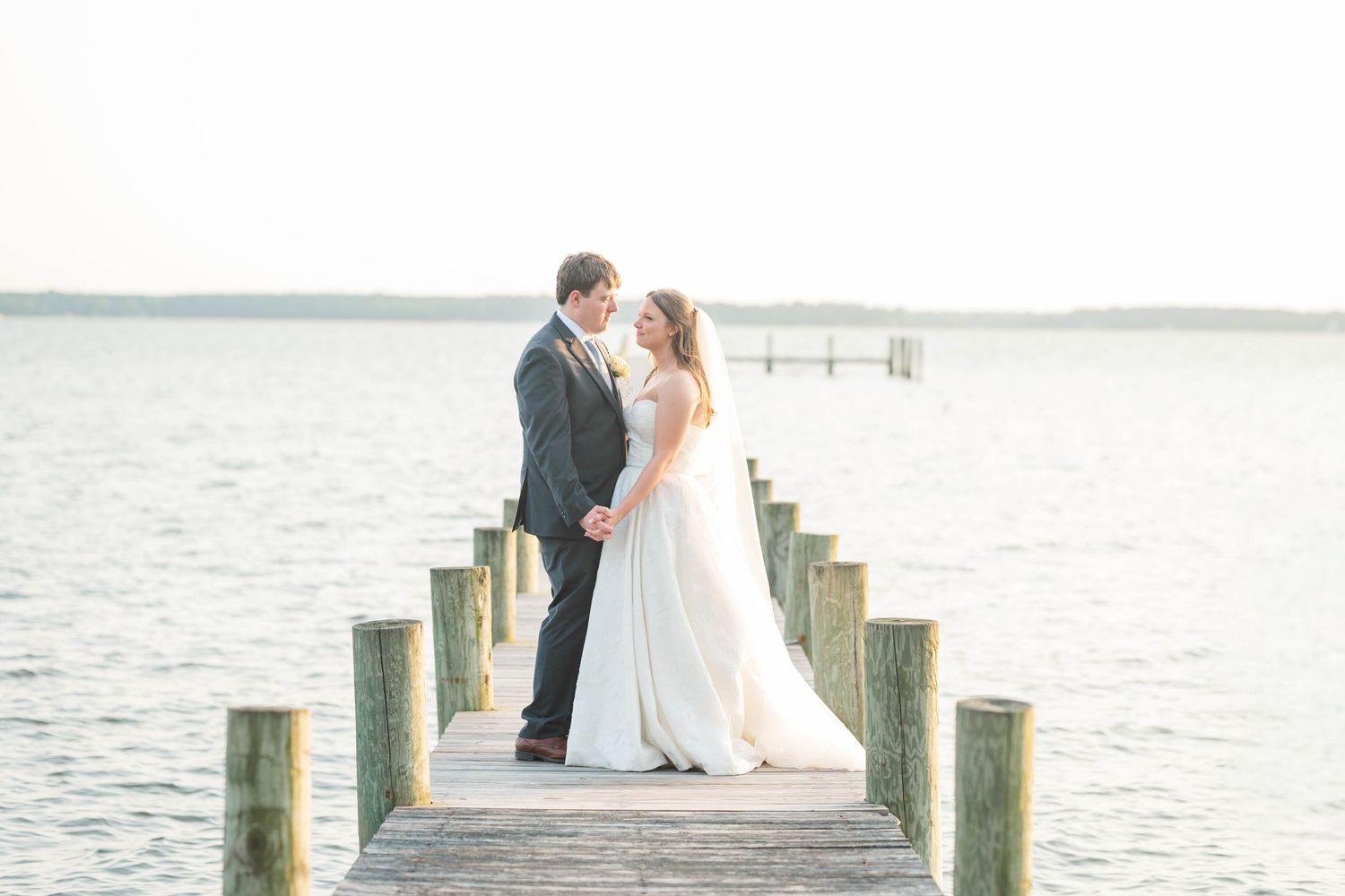 Romantic sunset portrait of newlyweds on a wooden dock by the water.
