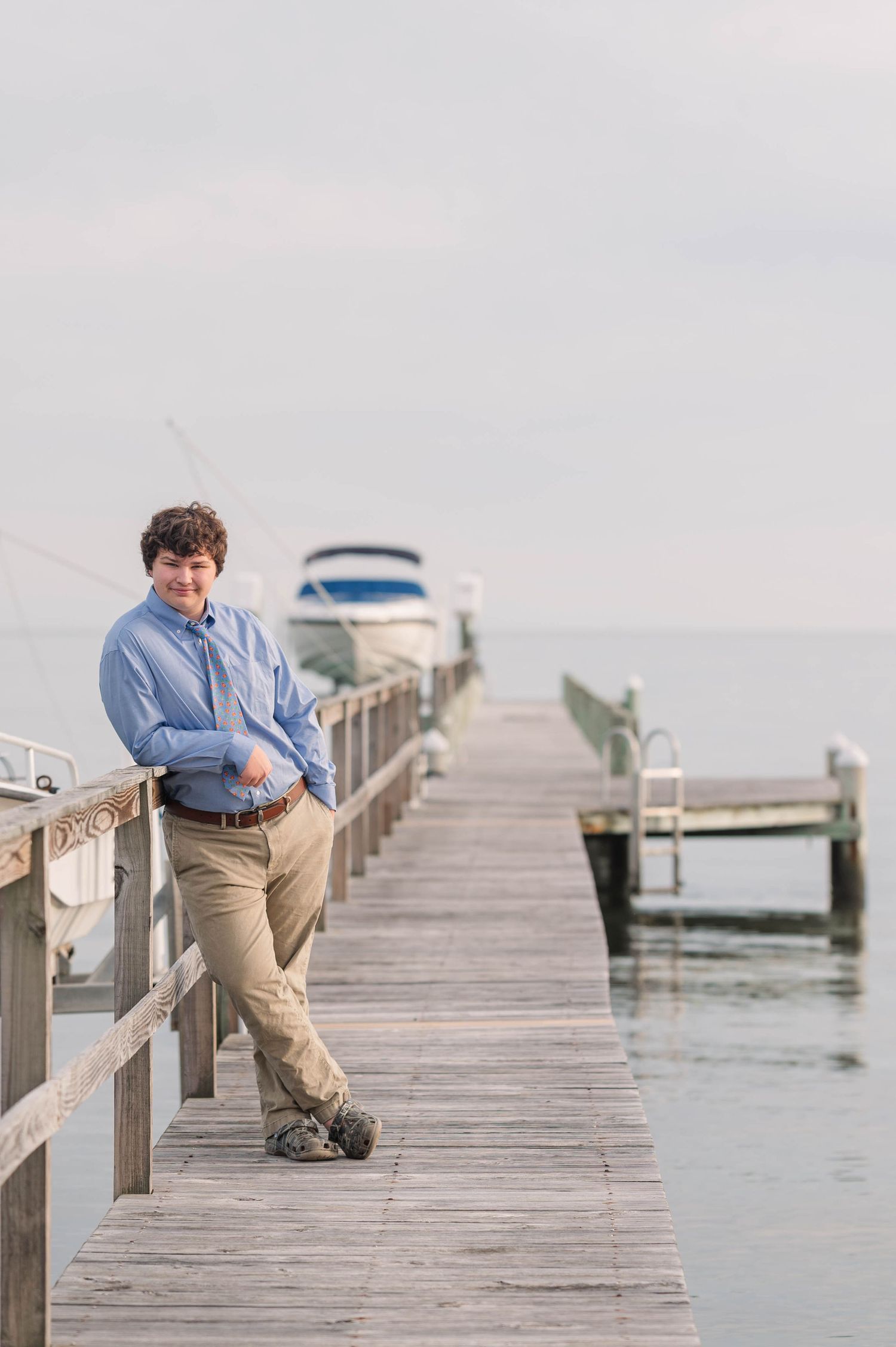 Person sitting alone on wooden dock overlooking peaceful water.