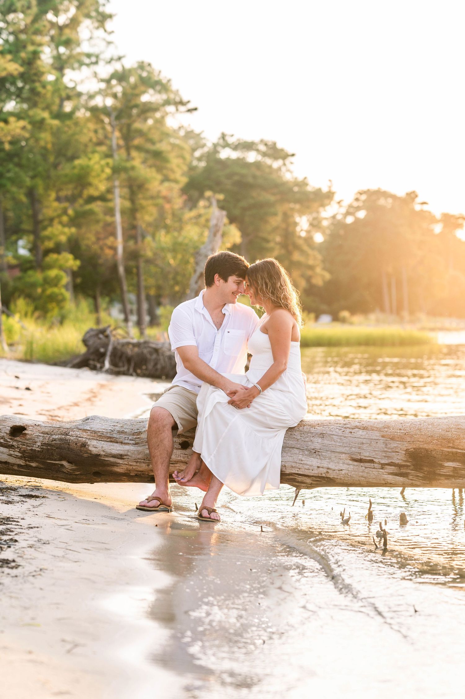 A sunset beach photoshoot with driftwood and golden hour lighting creating a romantic atmosphere.