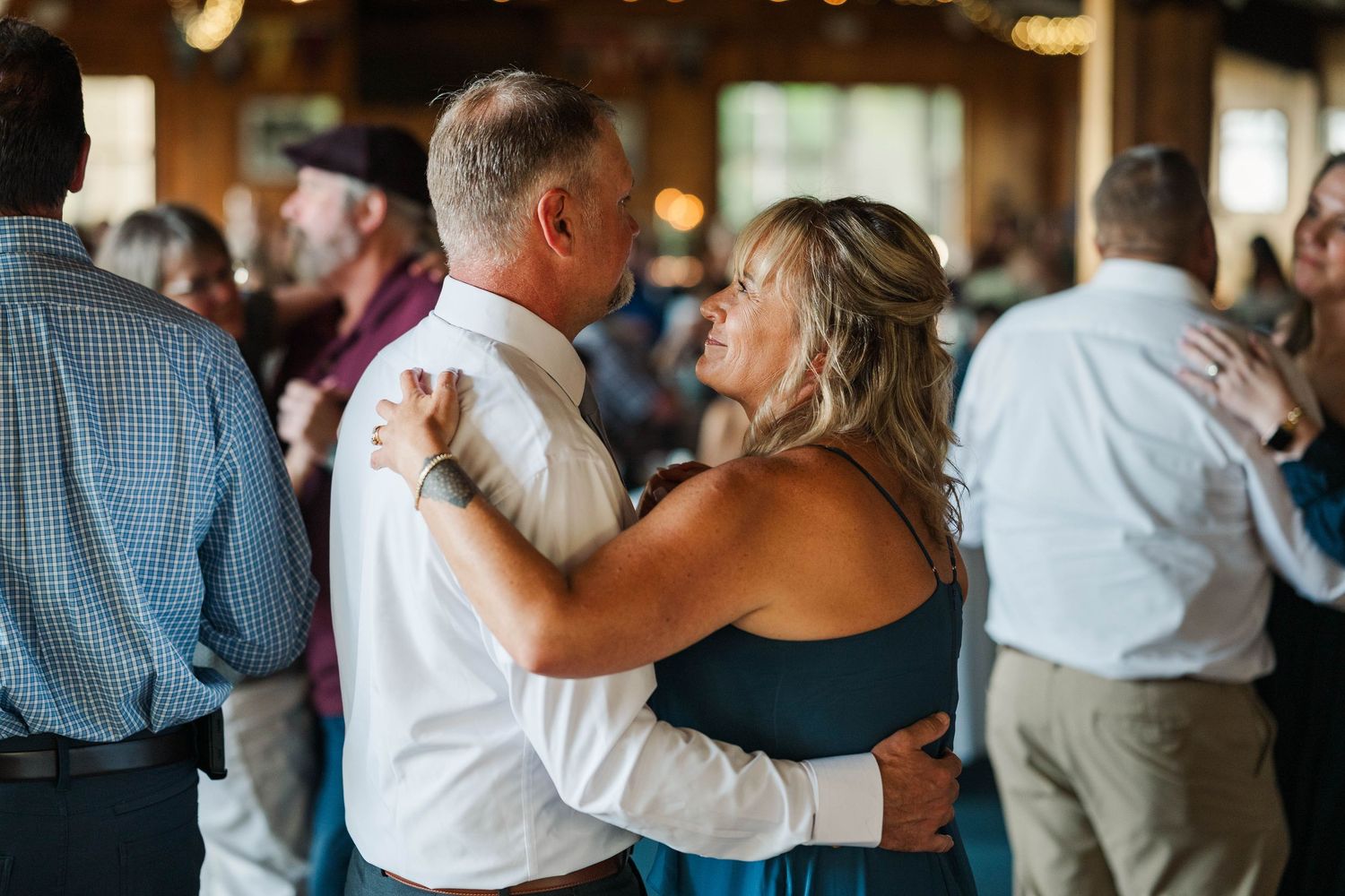 Couples dancing together at a wedding reception in a rustic barn venue.