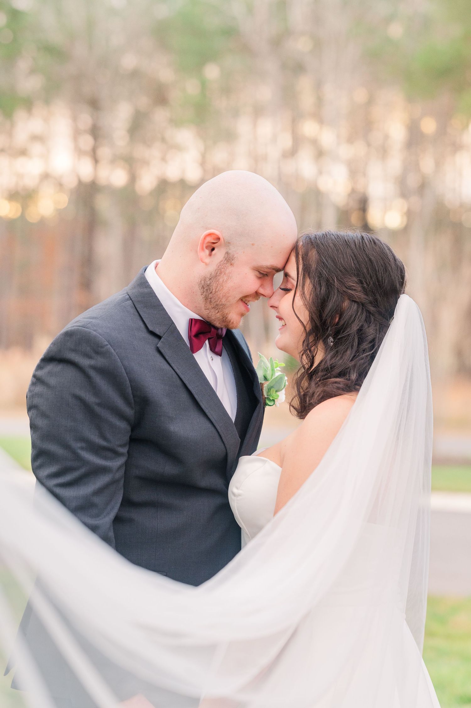 A romantic wedding portrait with flowing veil against a soft, natural background.
