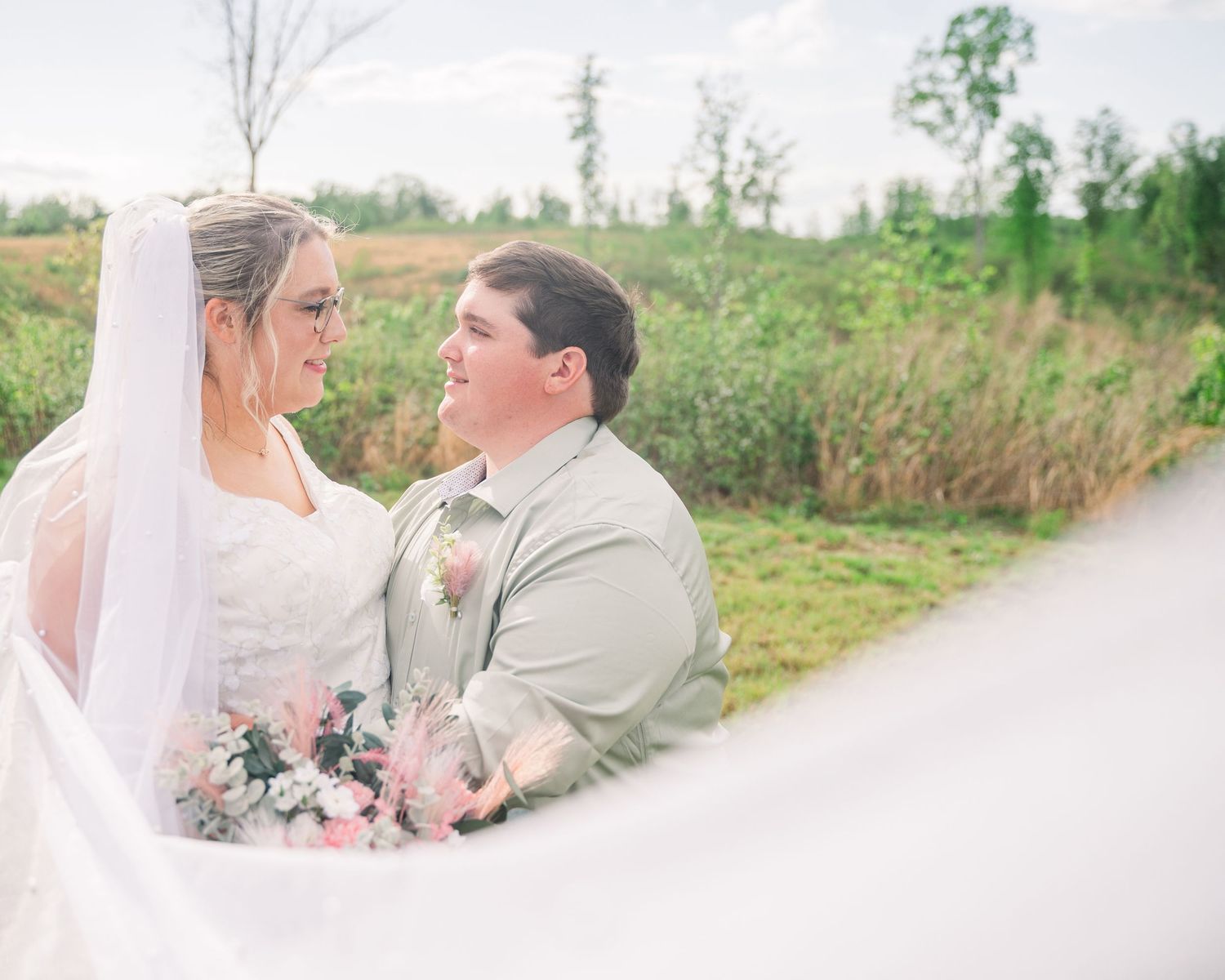An intimate wedding portrait captured through flowing white veil fabric.
