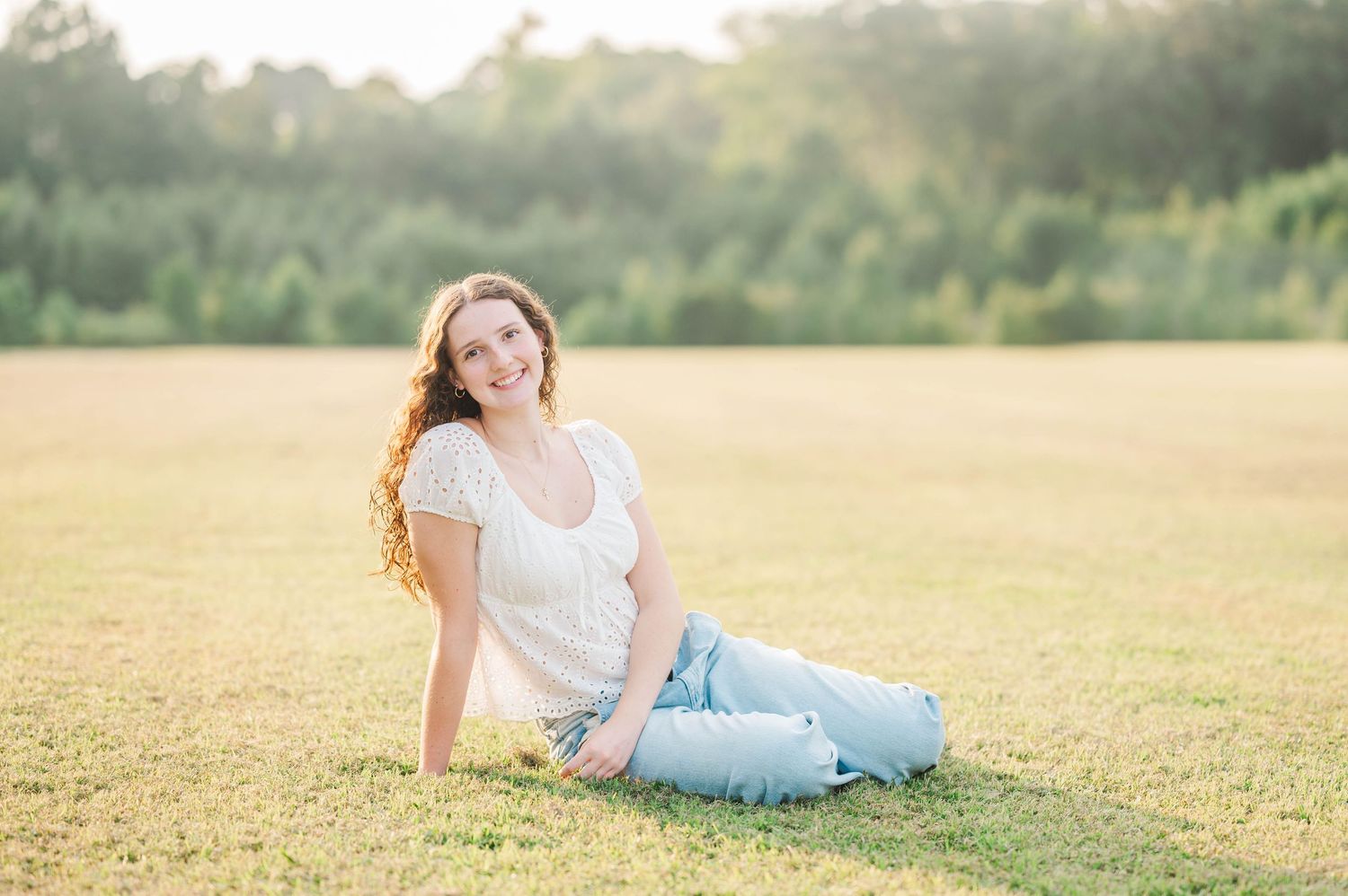 A person reclines in casual attire on grass during golden hour photography session.