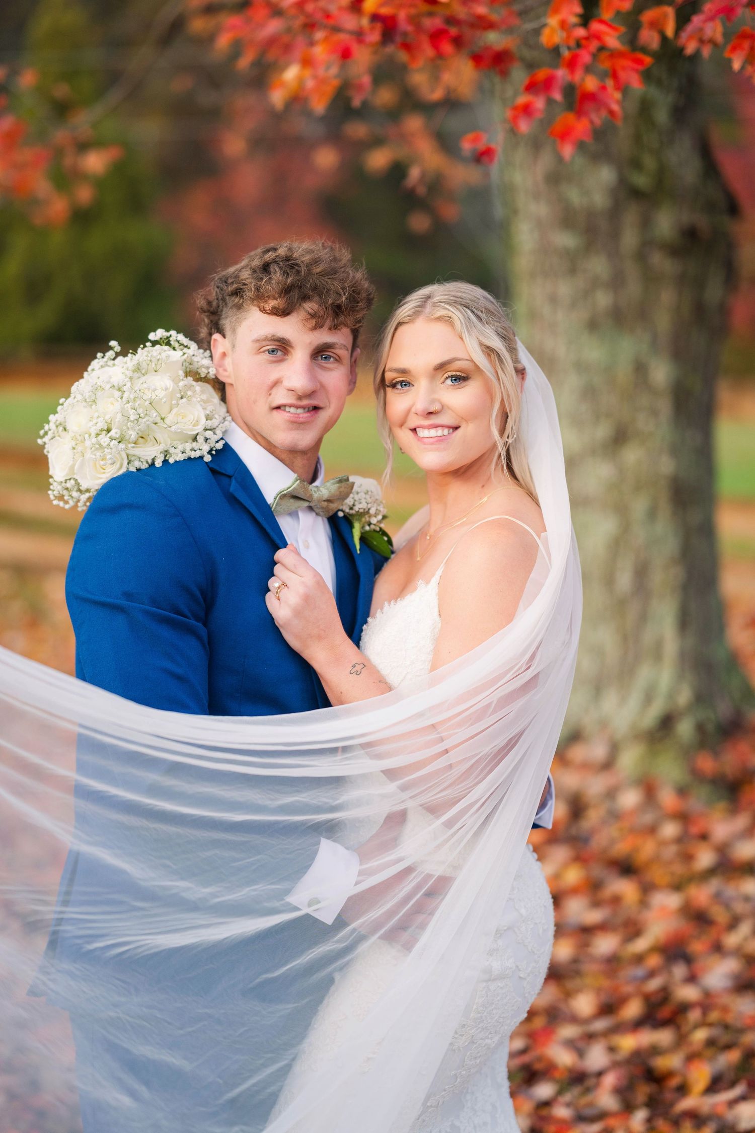 A romantic fall wedding photo series with autumn leaves and flowing veil captured in natural outdoor lighting.
