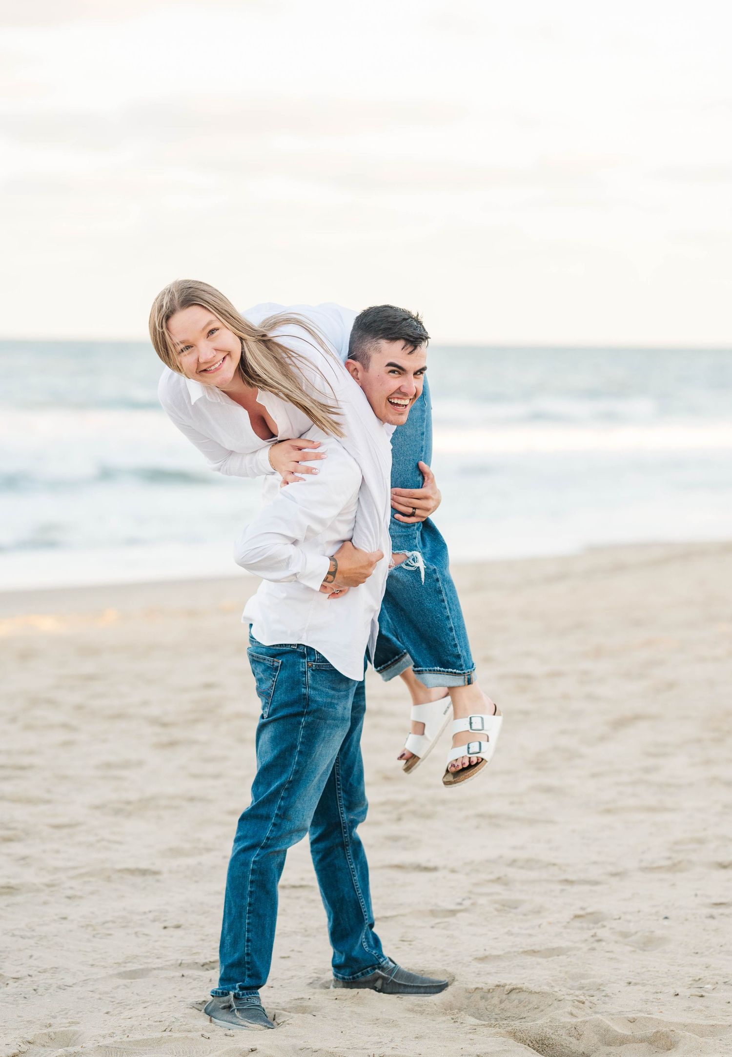 Joyful couple plays and spins on beach during golden hour.