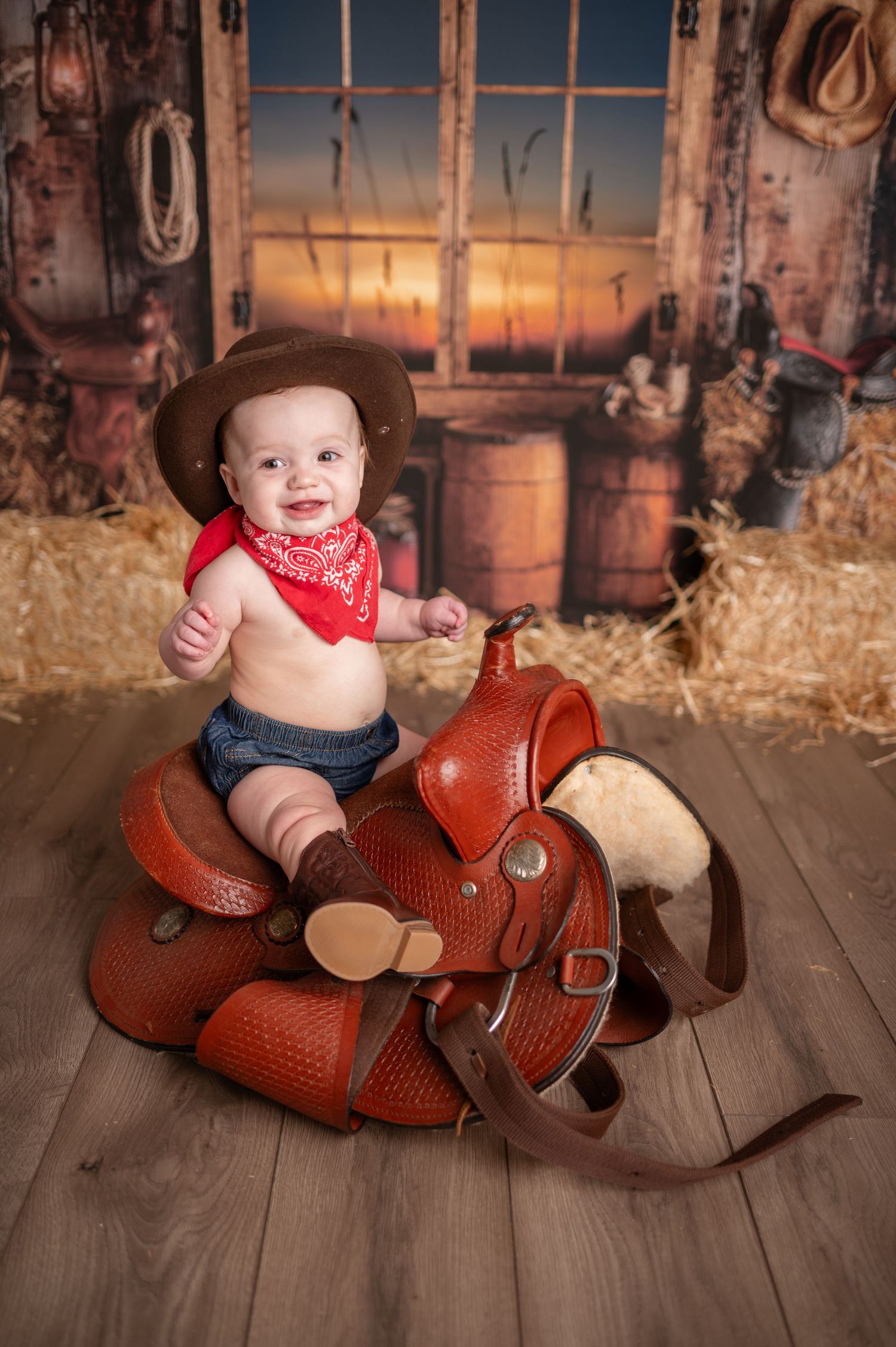 Western themed photo with leather saddle and rustic barn backdrop at sunset.
