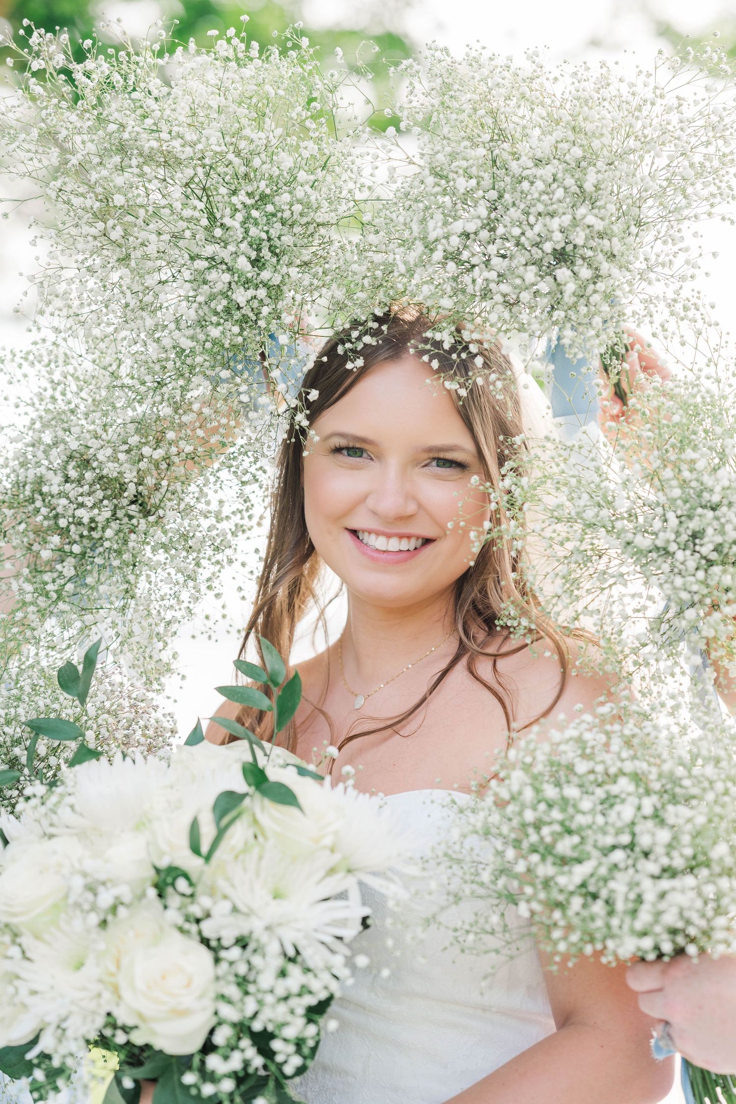 Delicate baby's breath crown frames a bridal portrait with white flowers.