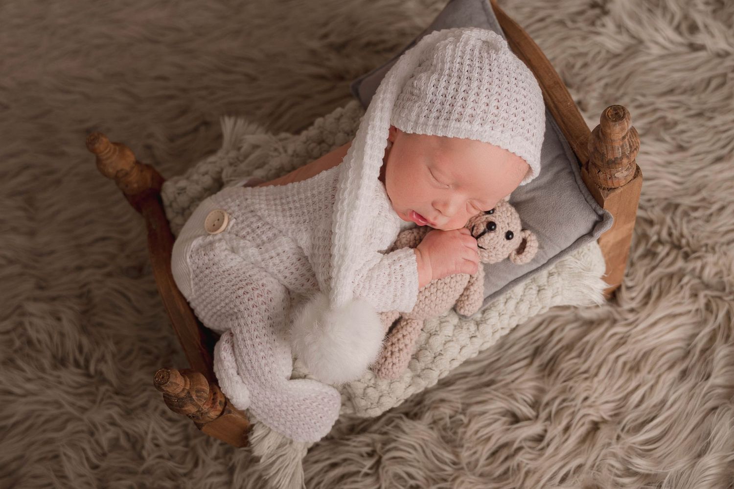 Cozy newborn photography setup with soft white blankets and textured rug.