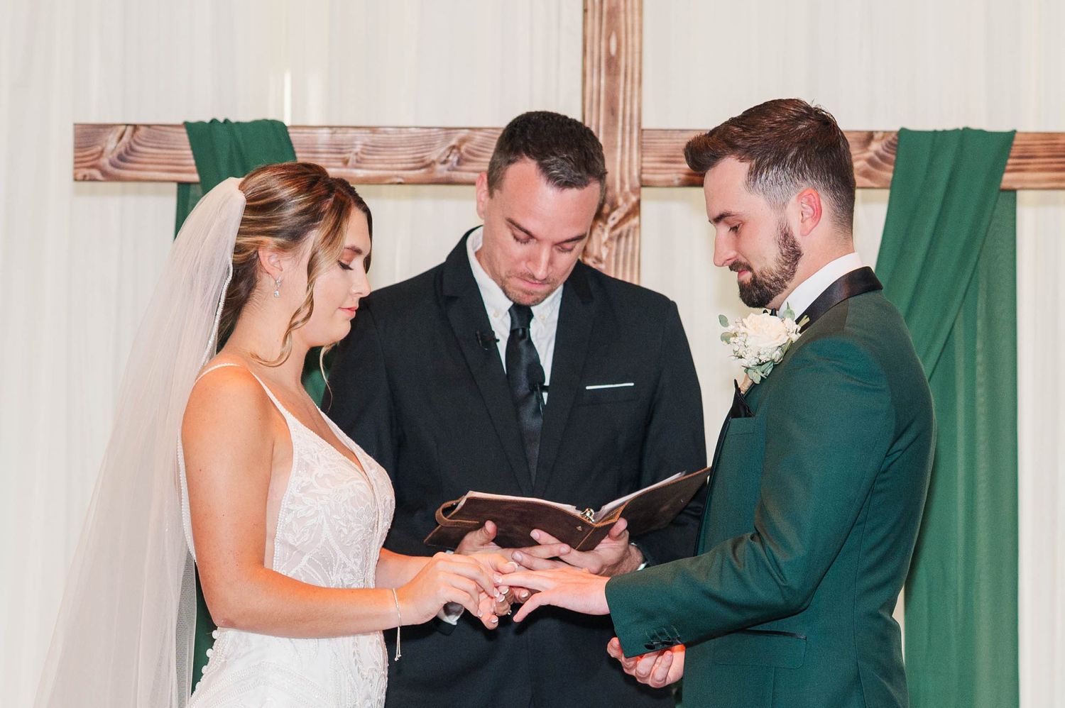 Wedding ceremony attendees standing together in formal wear with emerald green dresses.