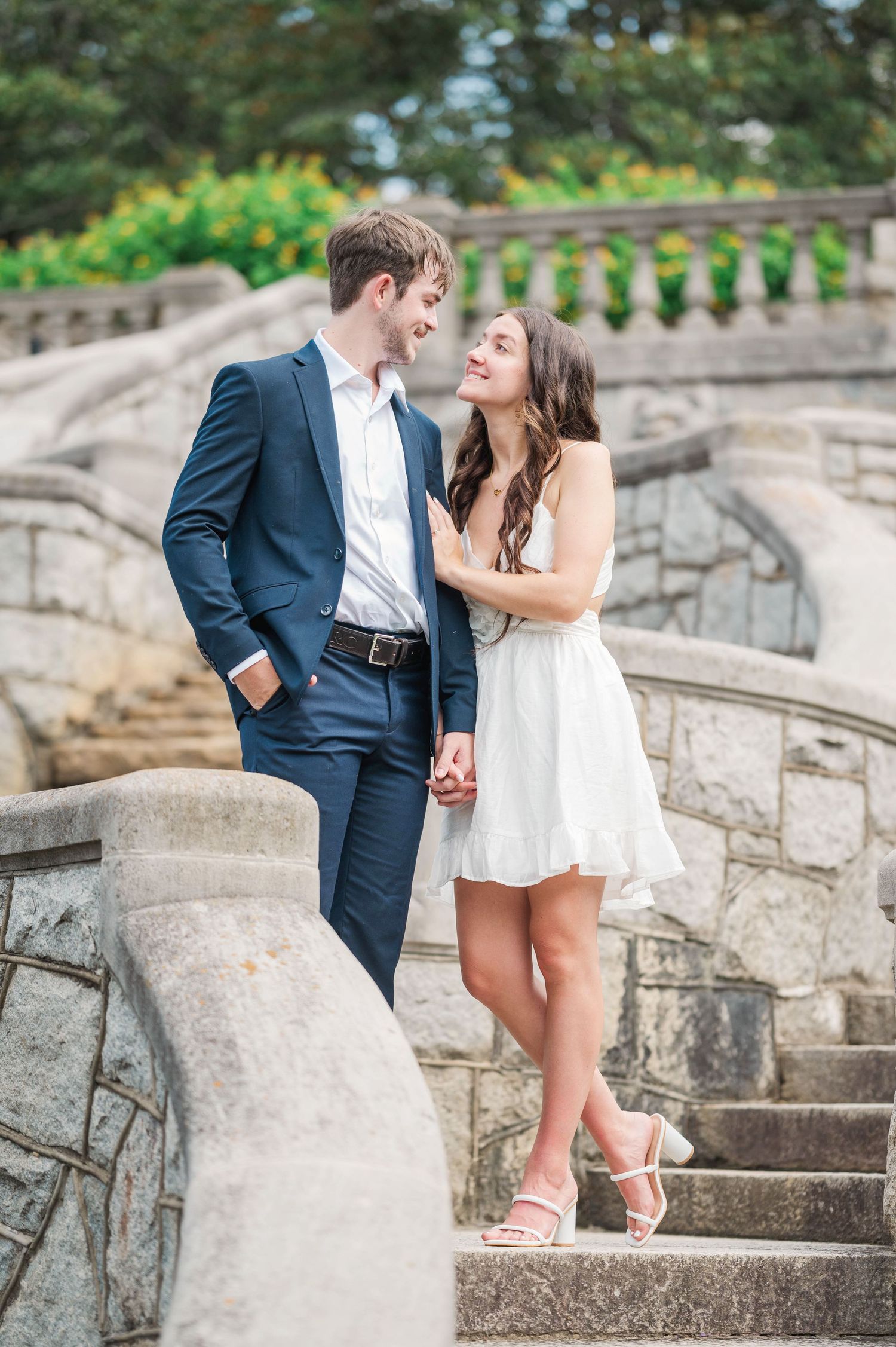 A romantic photoshoot on stone steps surrounded by lush greenery and natural lighting.
