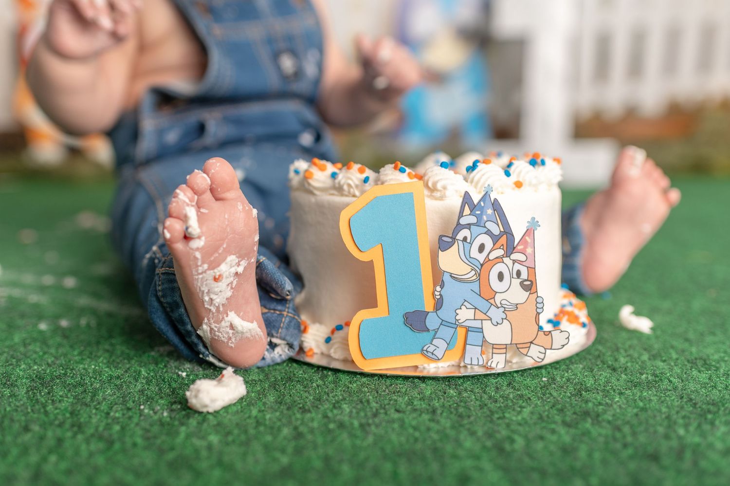 Close-up of destroyed birthday cake with scattered crumbs on artificial grass.