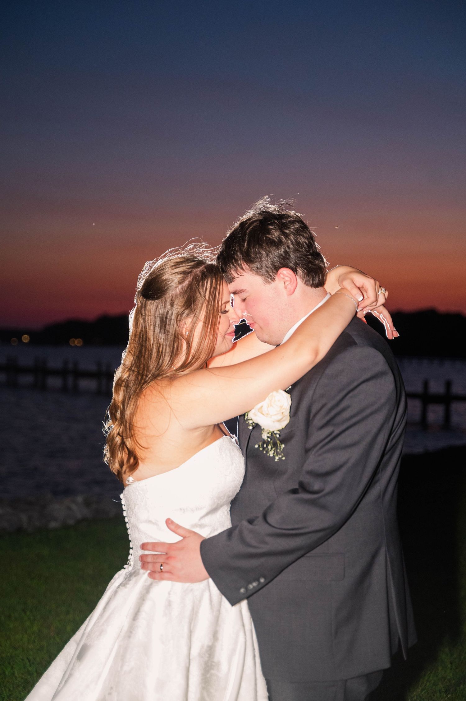 Romantic sunset silhouette of newlyweds sharing a kiss during their wedding photo session.