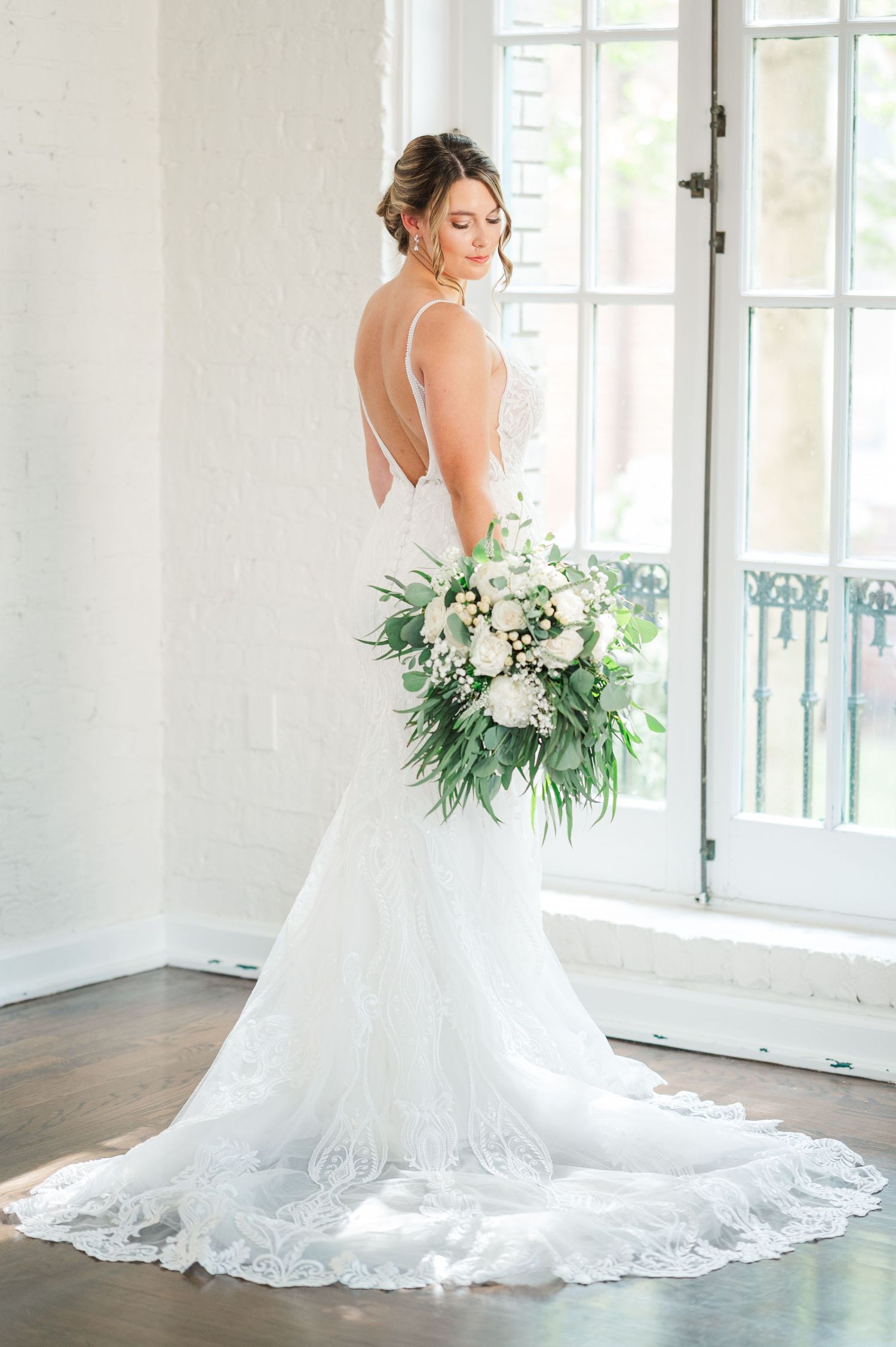 Elegant bridal portrait series showing lace wedding gown with dramatic train against white interior.