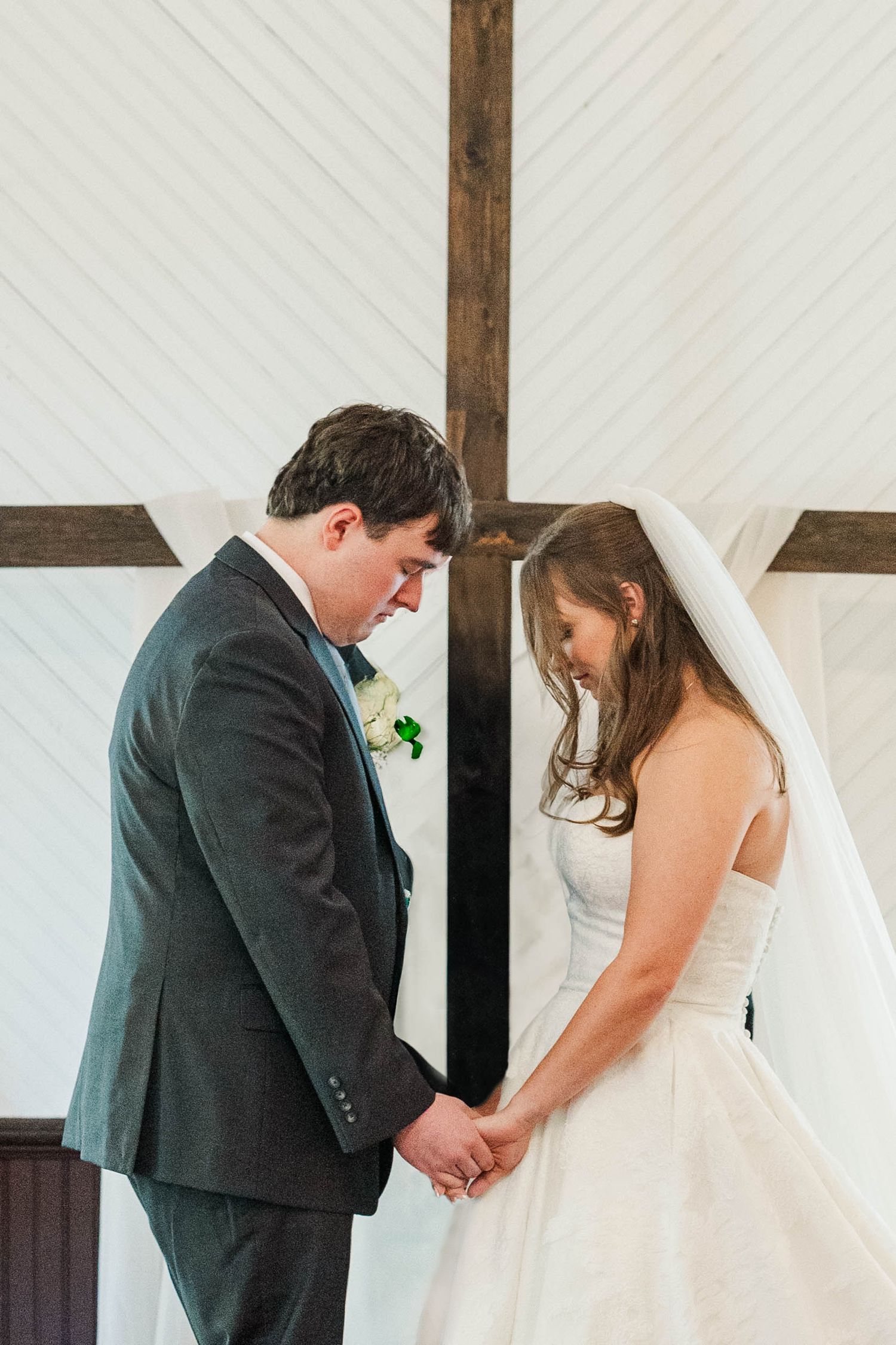 A tender moment during a wedding ceremony as the couple exchanges rings in front of a white backdrop.