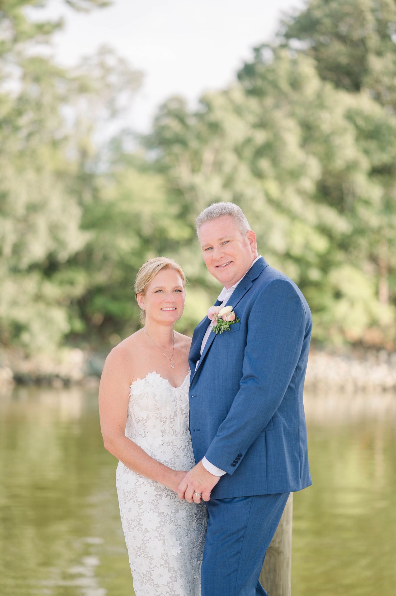 Wedding portraits by a lake with couple in formal attire.