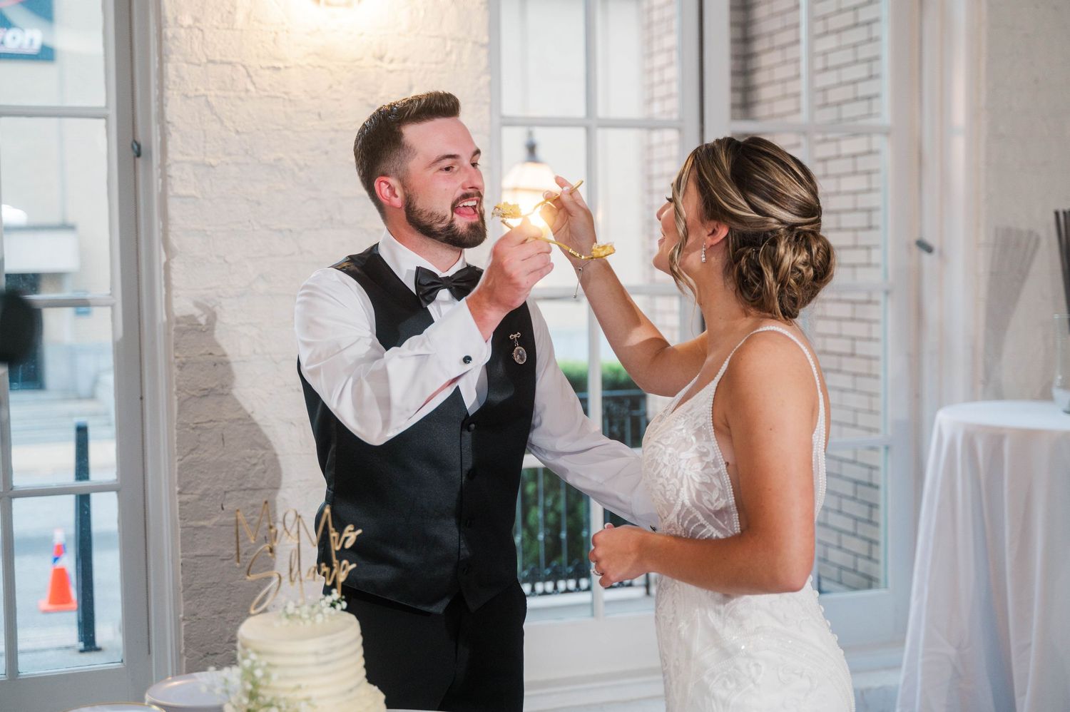 Wedding couple shares playful cake-feeding moments during their reception celebration.