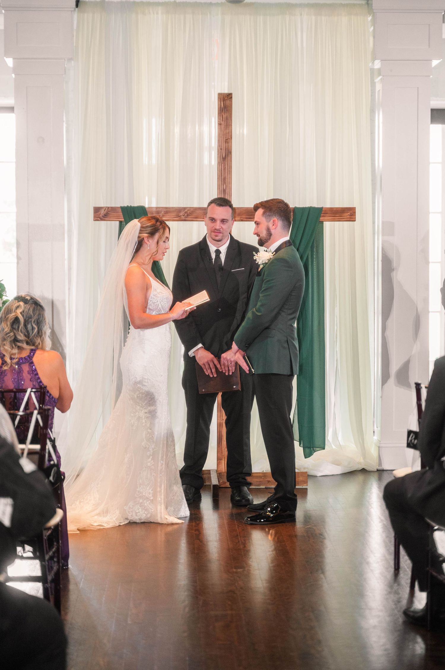 Wedding ceremony participants stand at the altar during an indoor service.