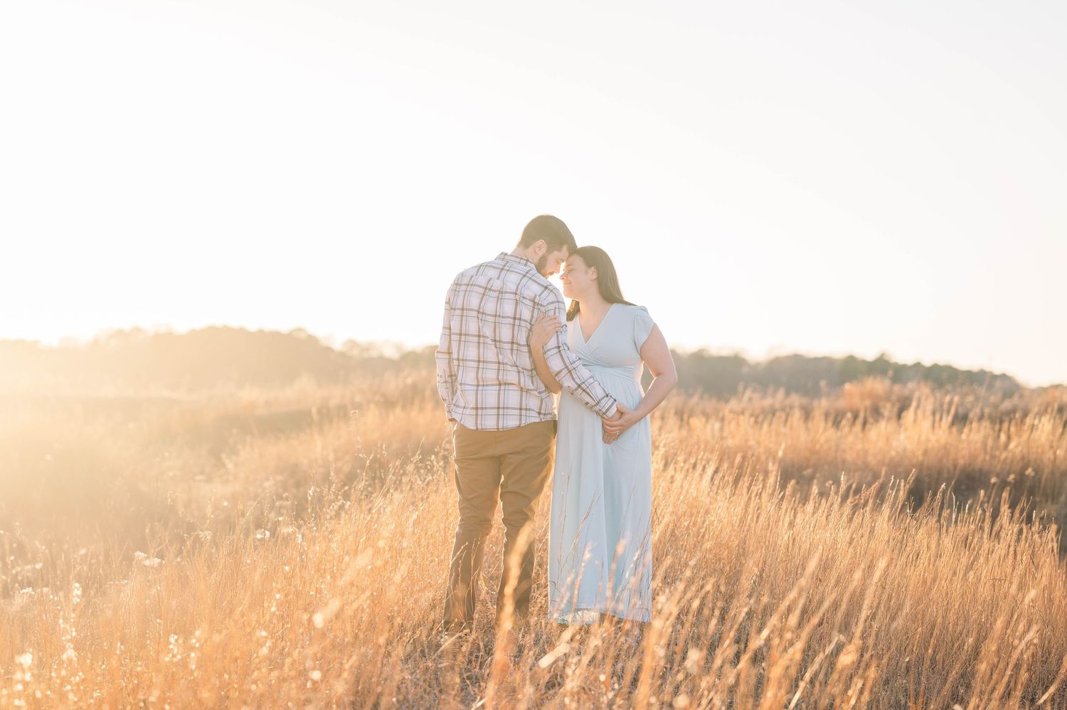 Couple sharing intimate moments in a golden wheat field at sunset.