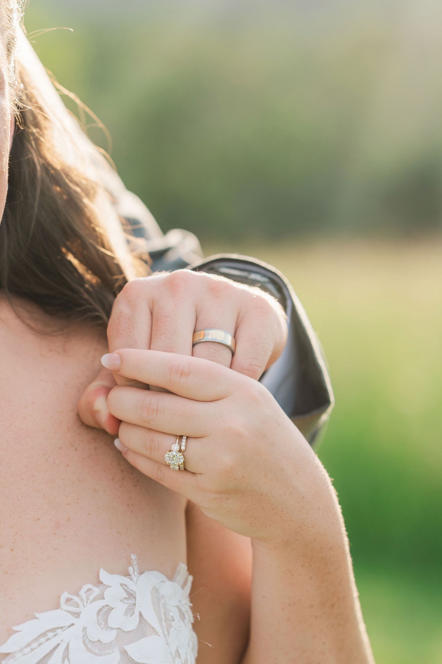 Close-up of bride and groom's hands showing wedding bands and diamond engagement ring on wedding day.