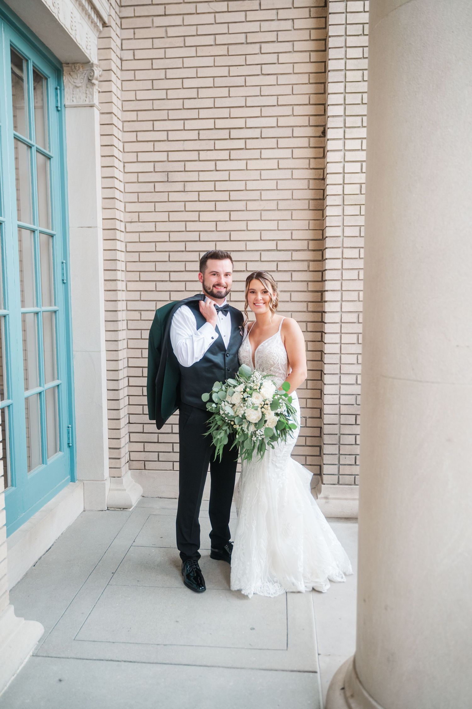 A couple shares a romantic moment in a covered walkway with turquoise window trim.