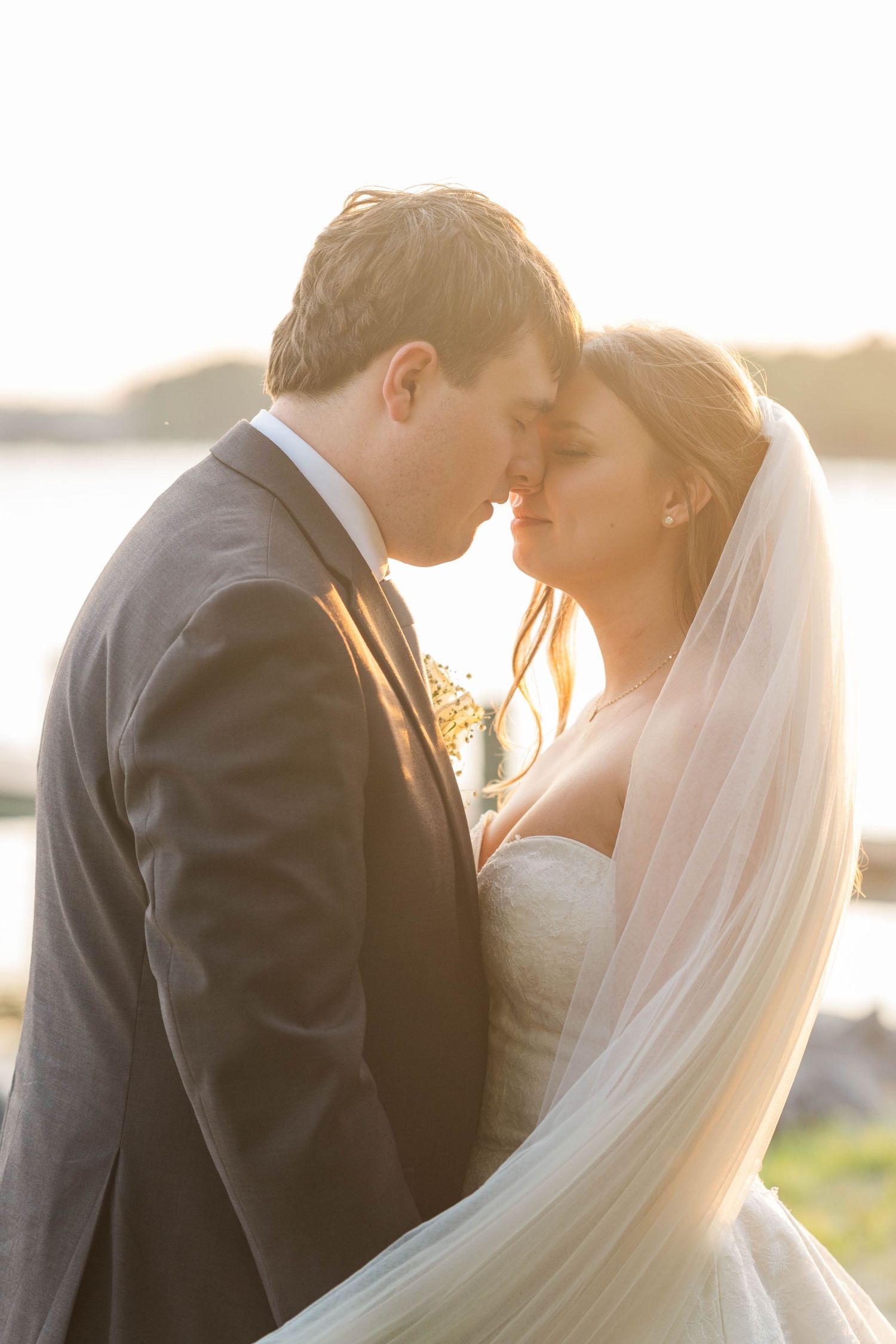 Intimate sunset portrait of a couple in wedding attire with soft golden light.