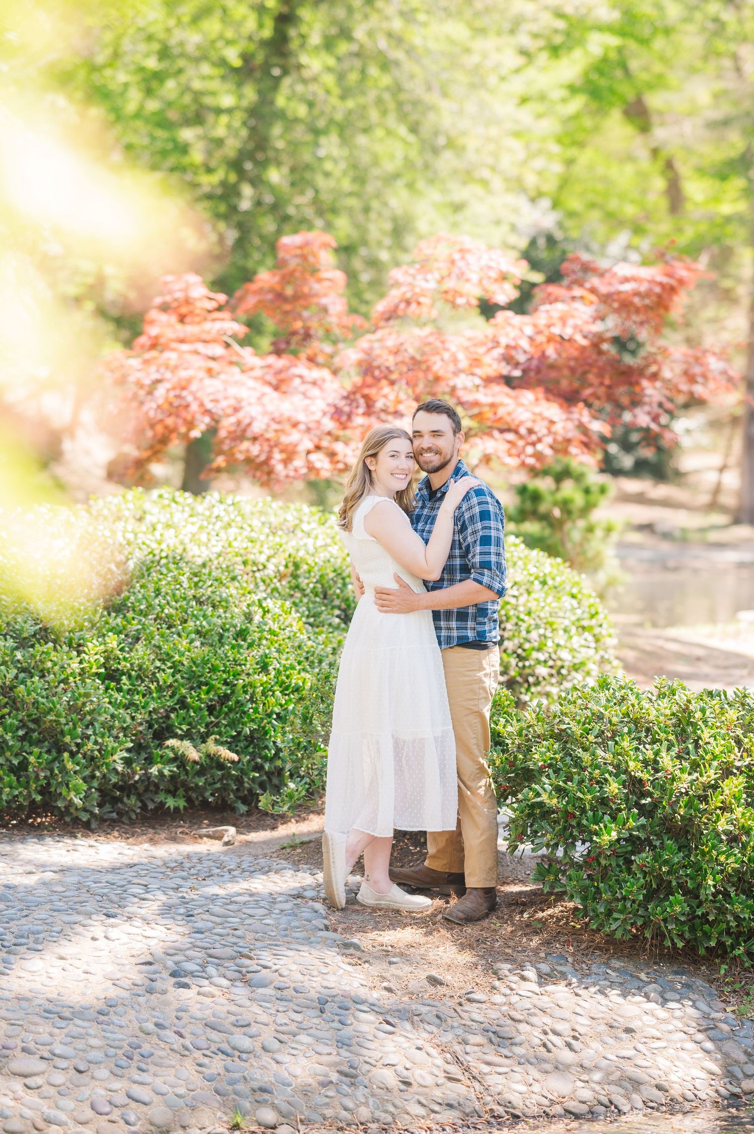 A springtime engagement session with blooming pink flowers and cobblestone pathways.