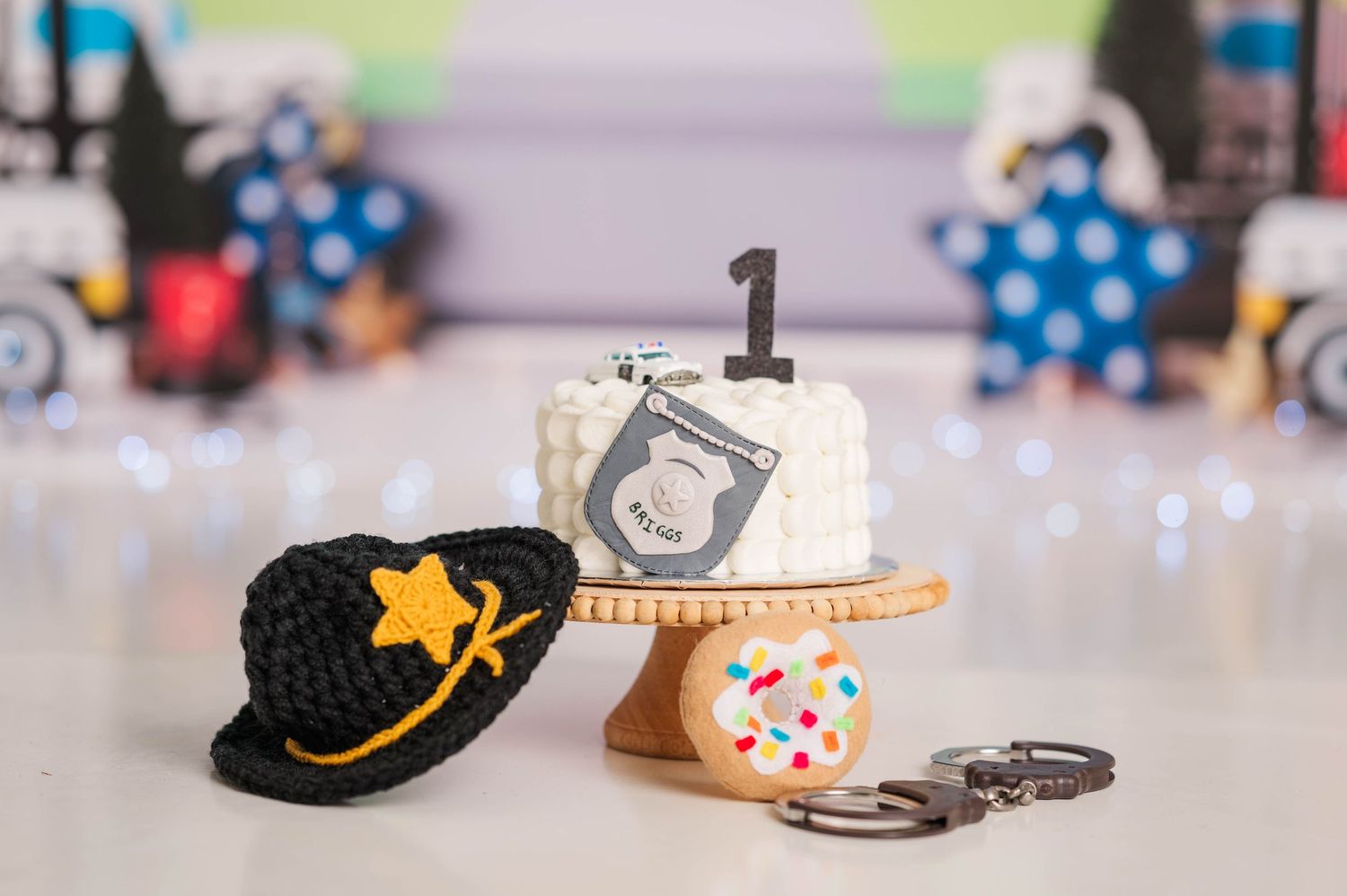 Close-up of police themed party decorations including a hat and handcuffs on a blurred background.