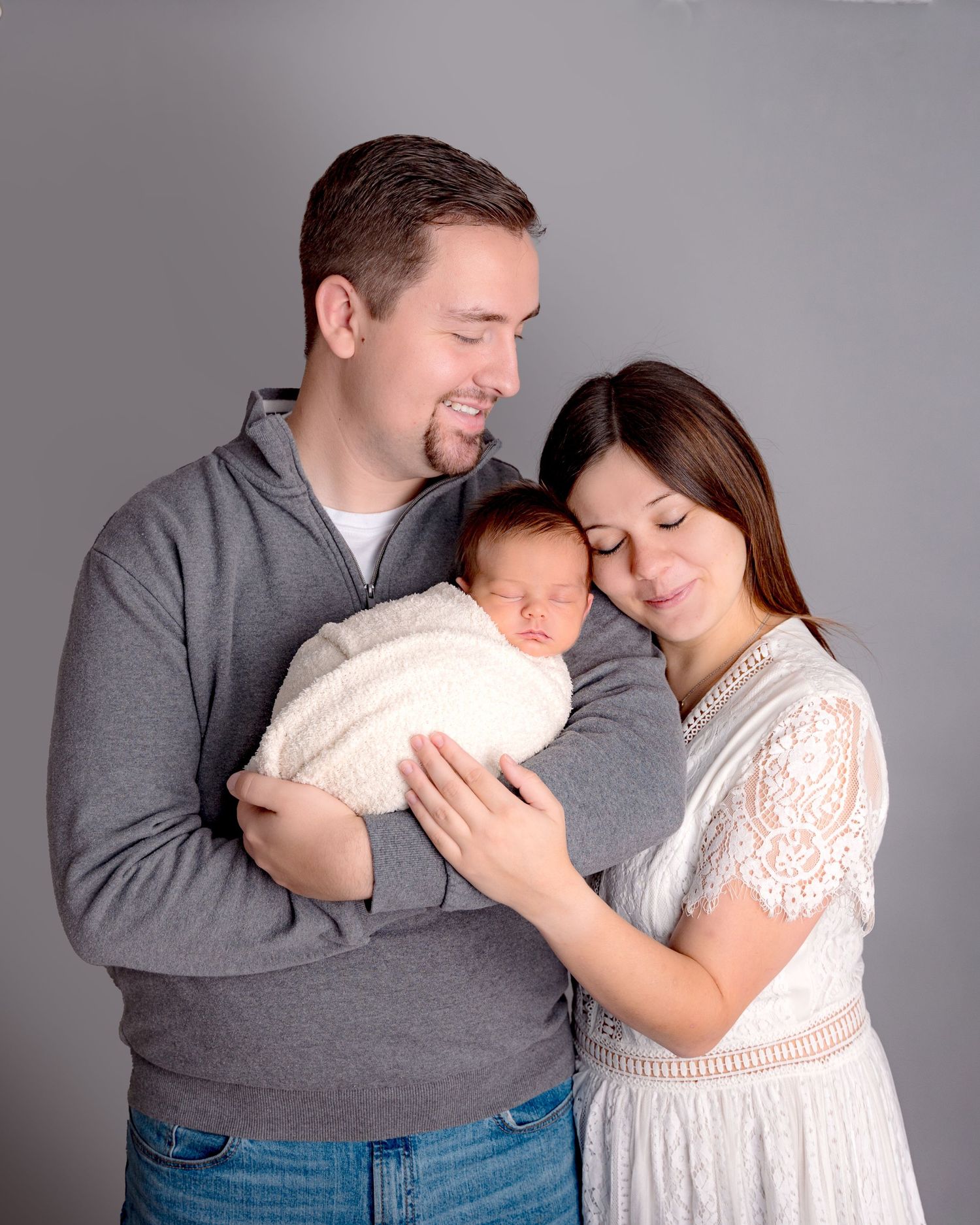 A couple in grey and white outfits embrace tenderly in a series of intimate studio portraits.