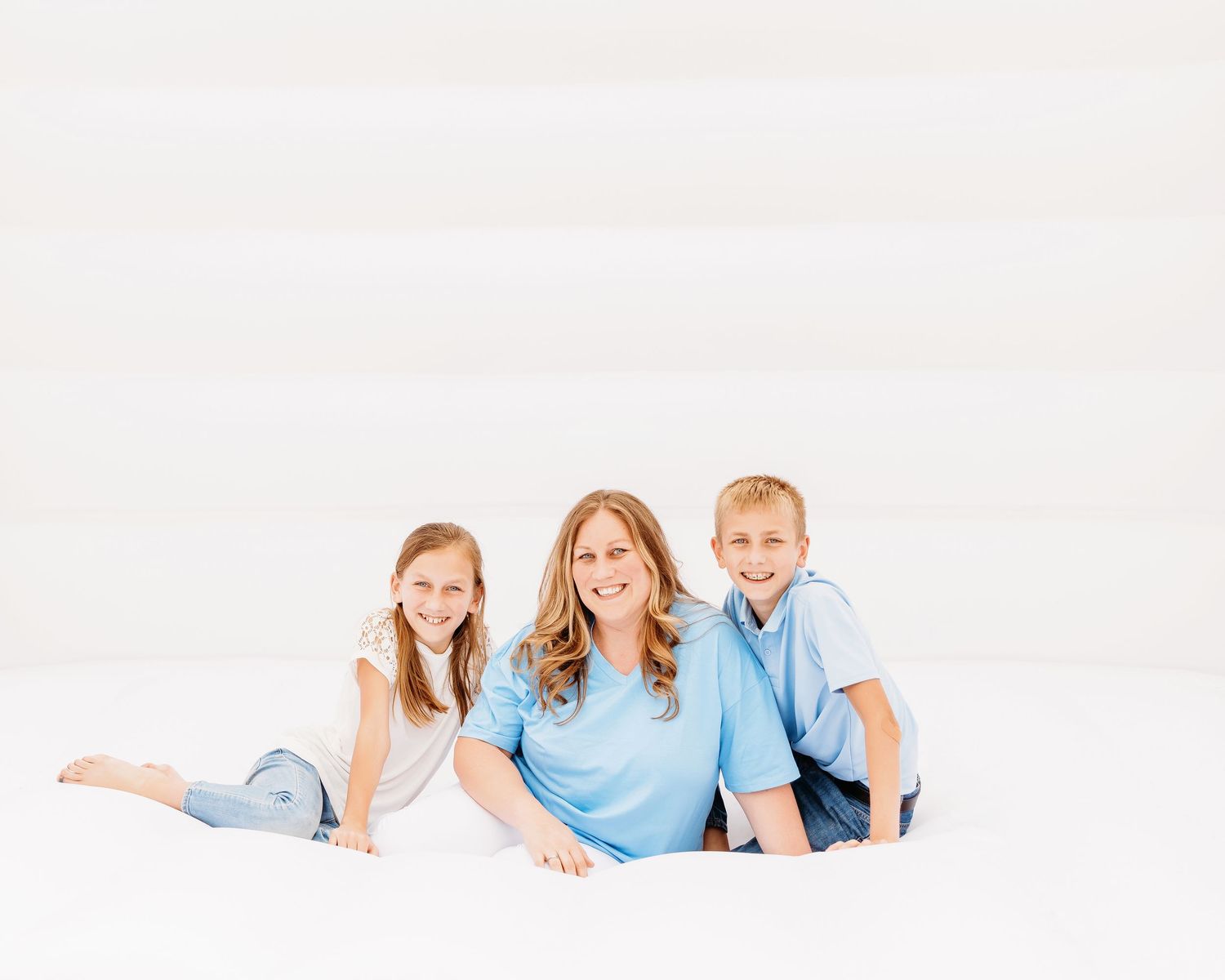 Family portrait session with coordinating blue and white outfits against white background.