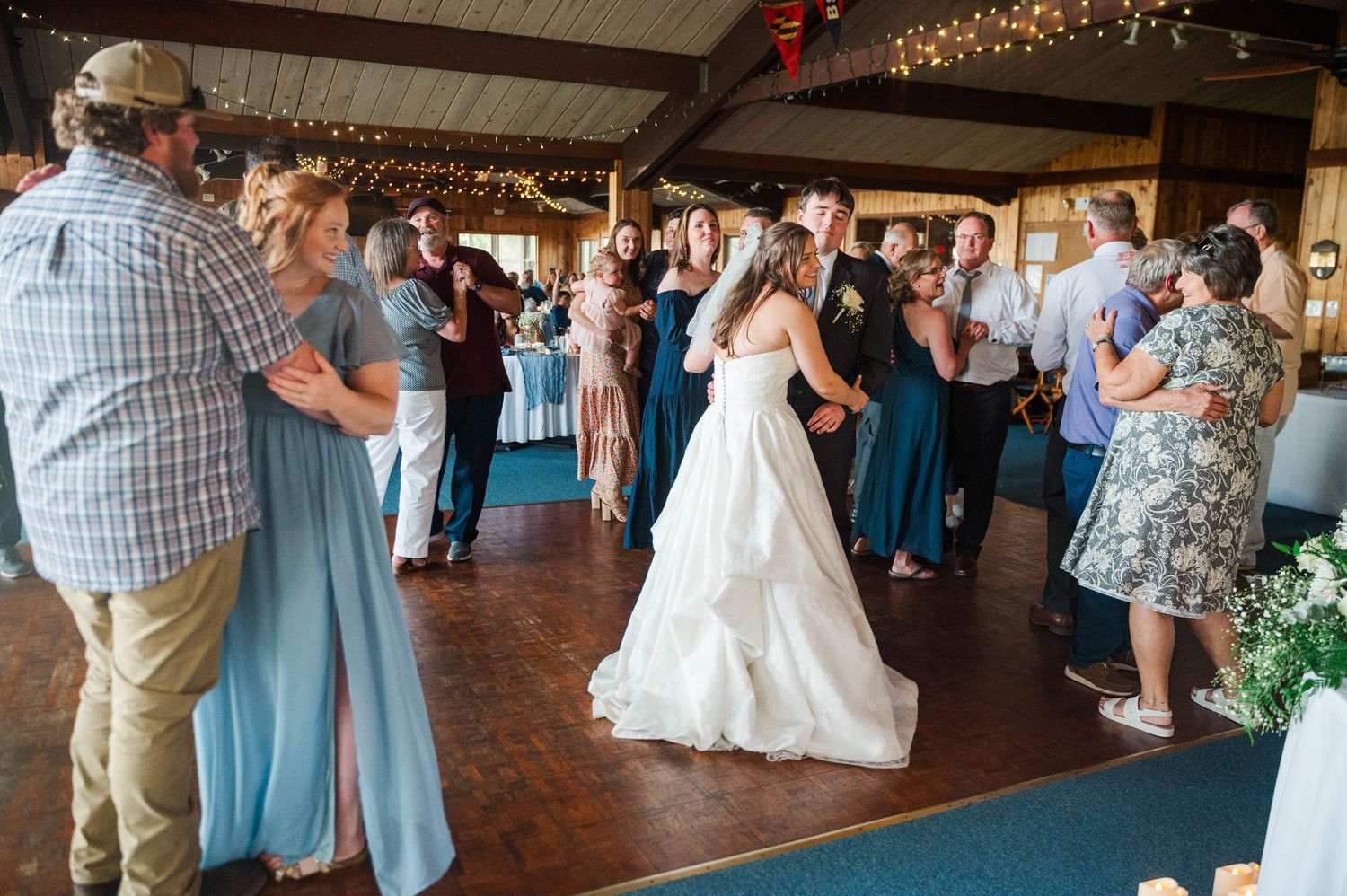 Wedding reception venue with rustic wooden beams and twinkling string lights overhead.
