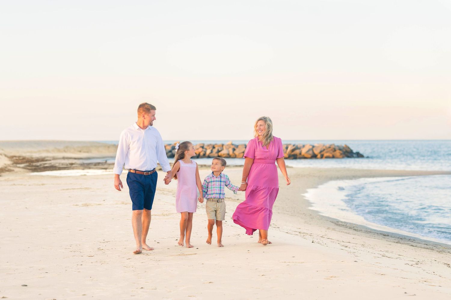 Family walking along shoreline during sunset beach photoshoot.