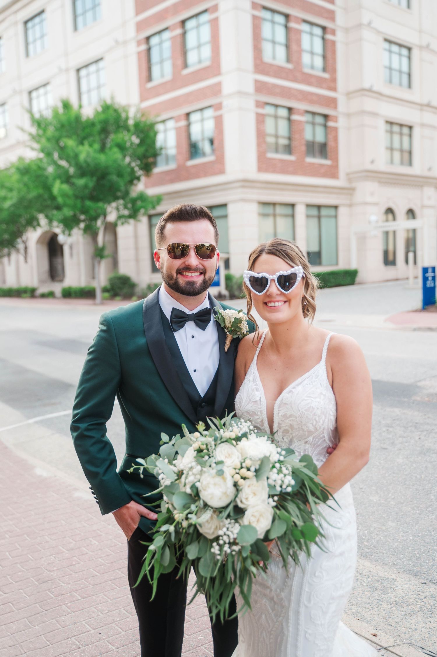 Outdoor wedding portraits with couple in formal attire holding white floral bouquet.