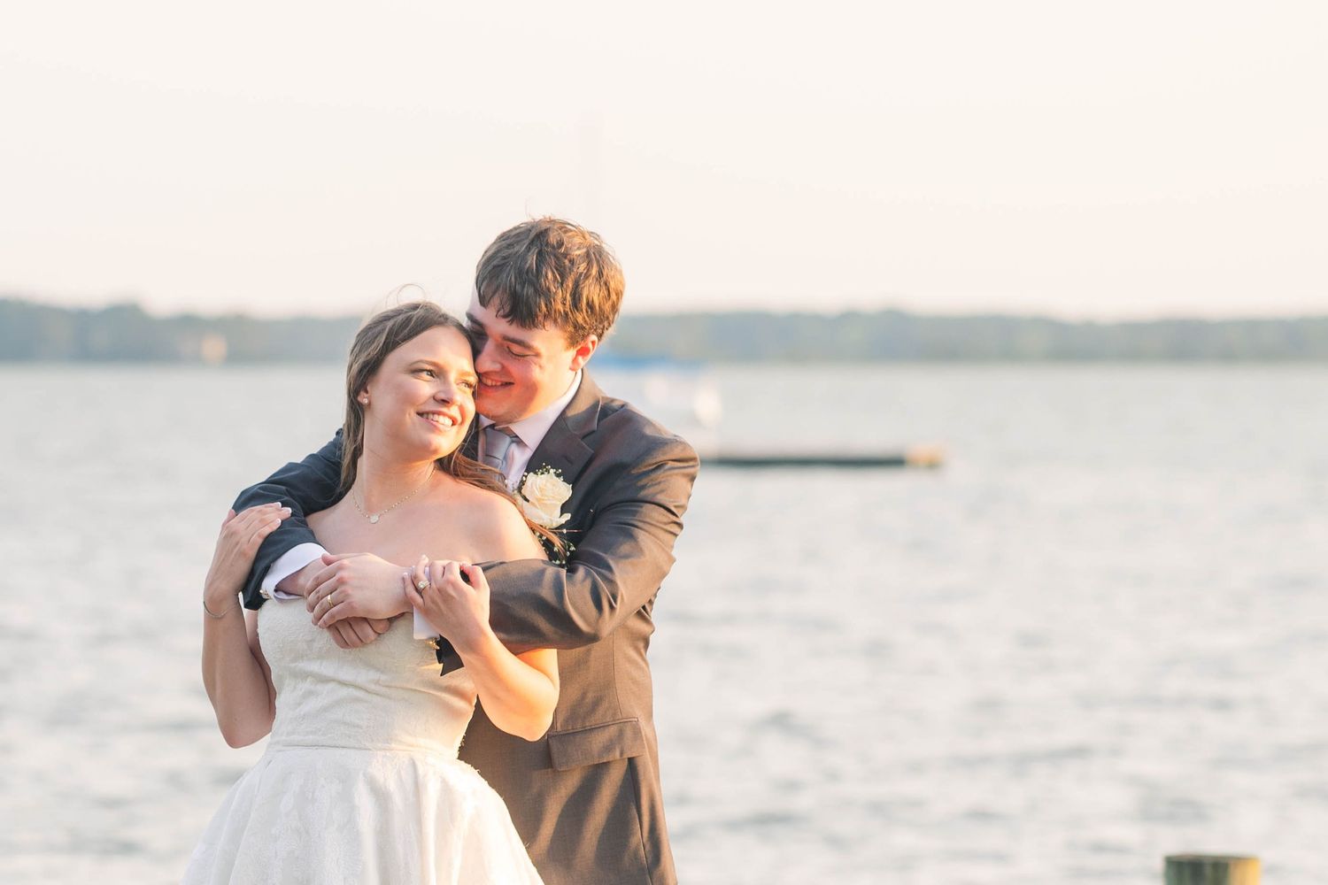 Couple shares a playful dance moment on a dock during their sunset wedding photoshoot.